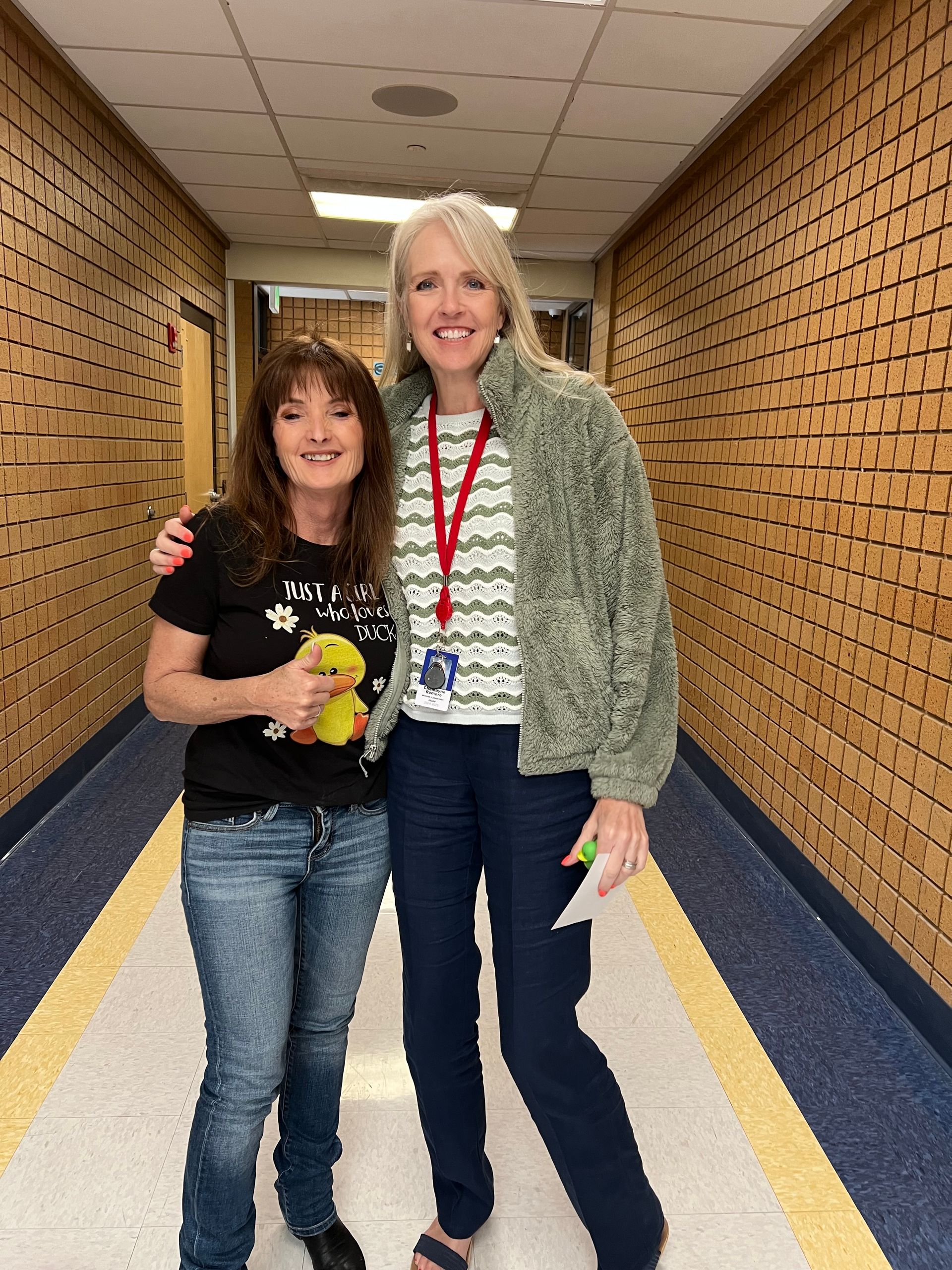 Two women are posing for a picture in a hallway.