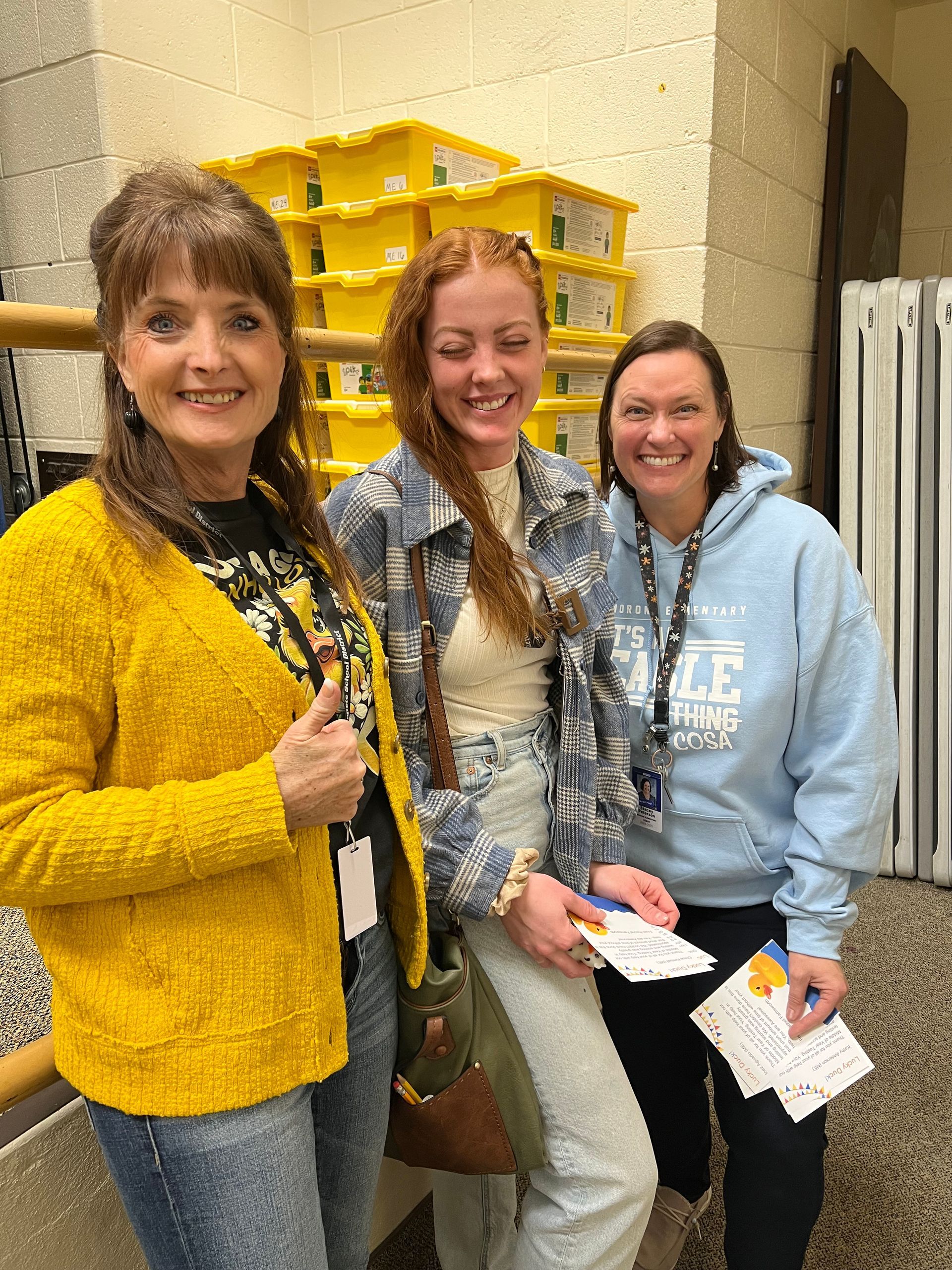 Three women are posing for a picture together in a hallway.