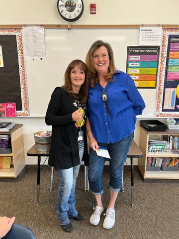 Two women are standing next to each other in a classroom.