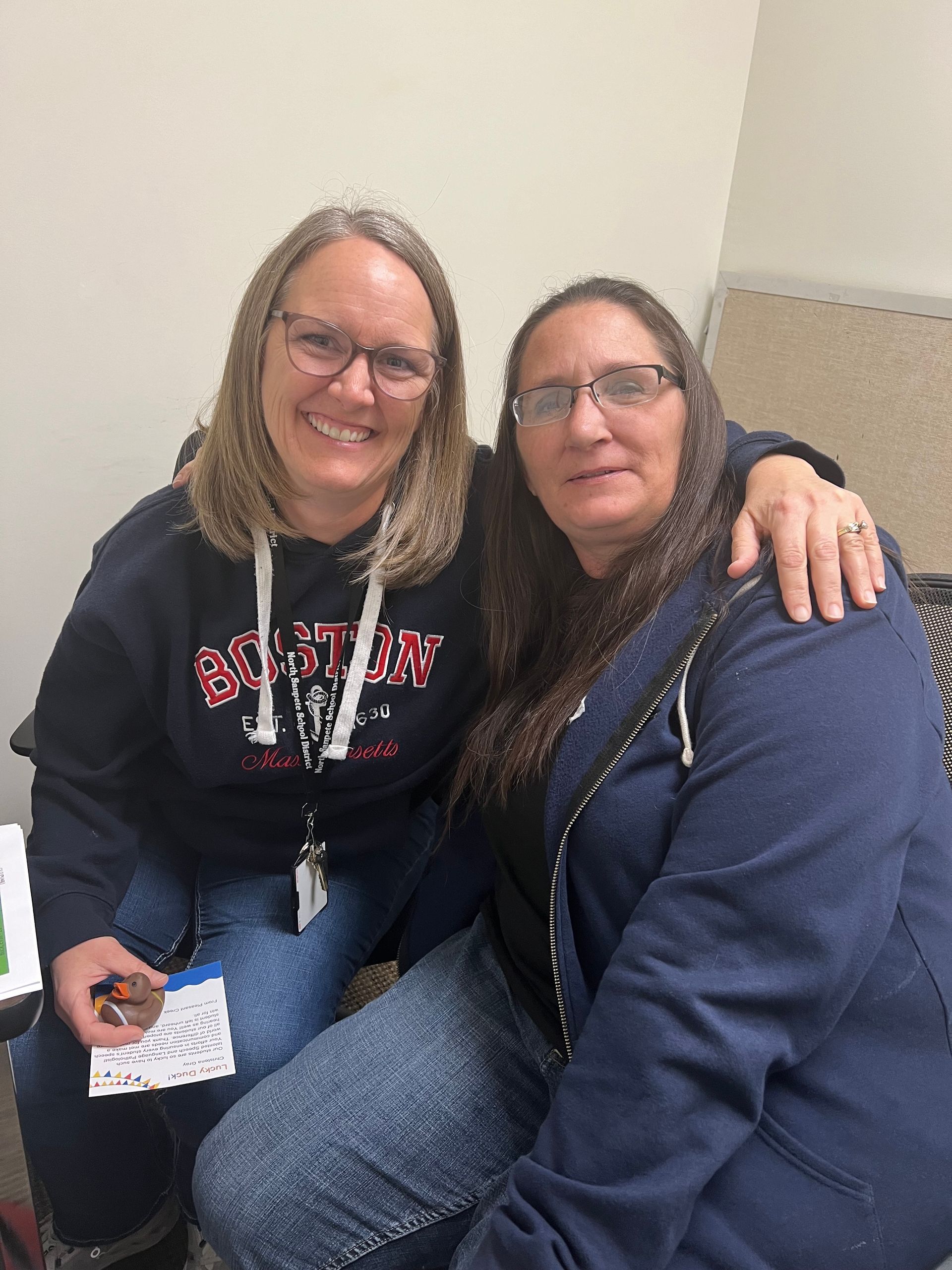 Two women are sitting next to each other and smiling for the camera.