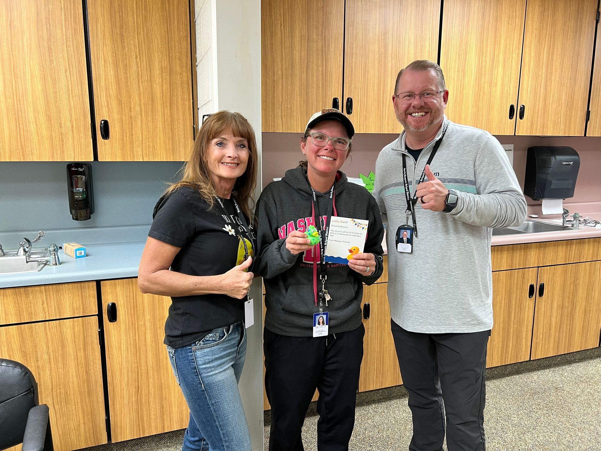 Three people are posing for a picture in a kitchen.