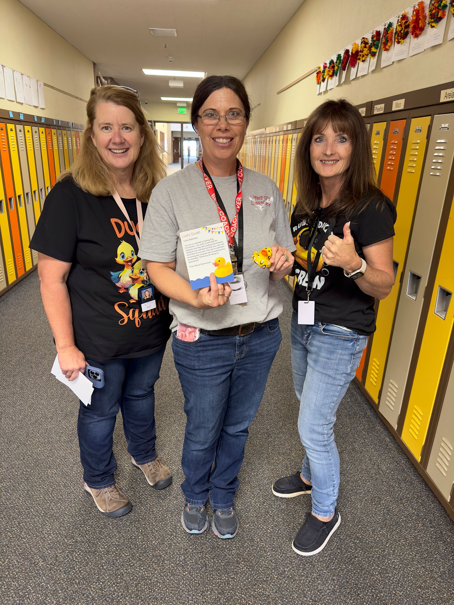 Three women are standing next to each other in a hallway.