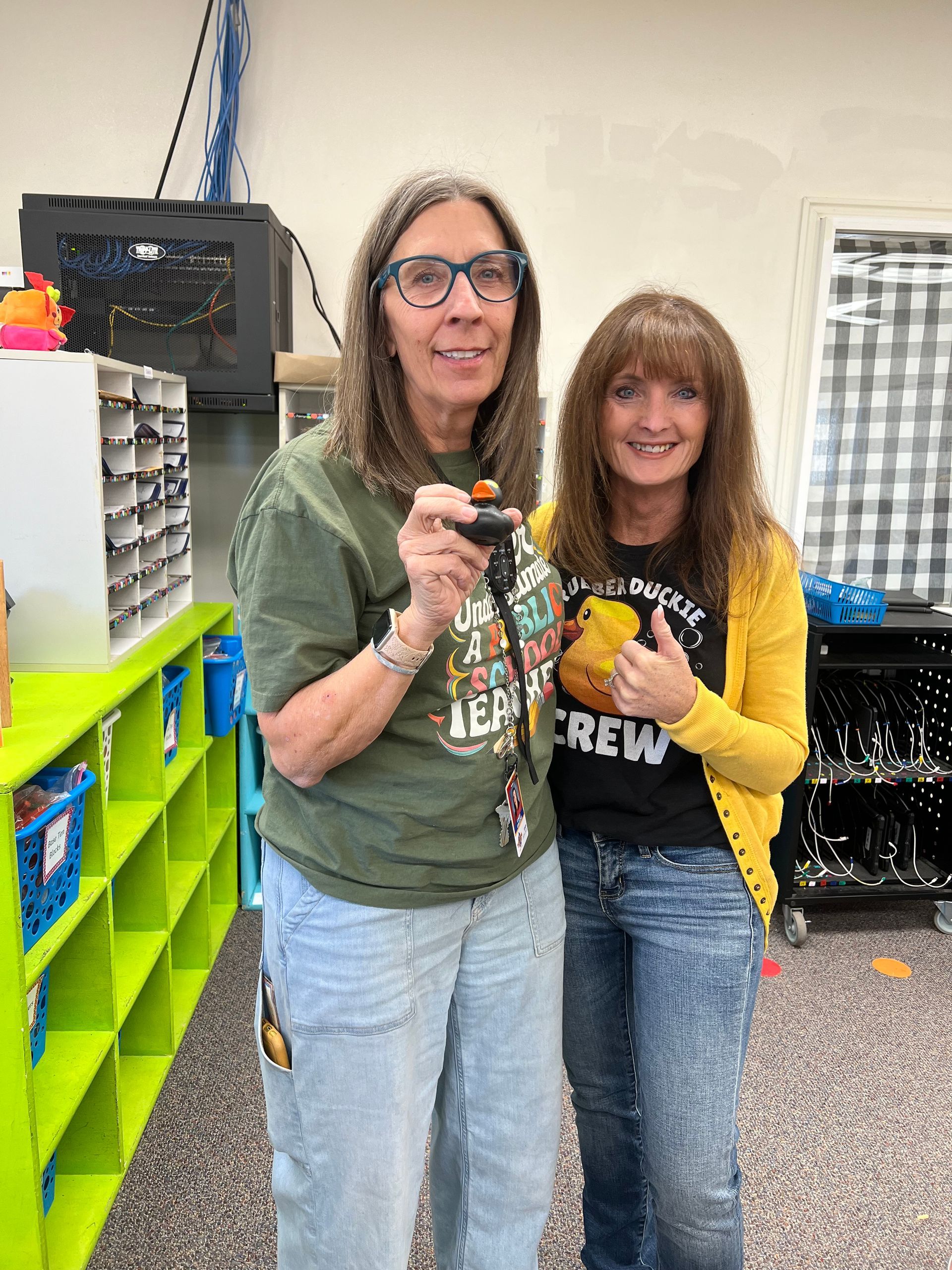 Two women are standing next to each other in a classroom holding keys.