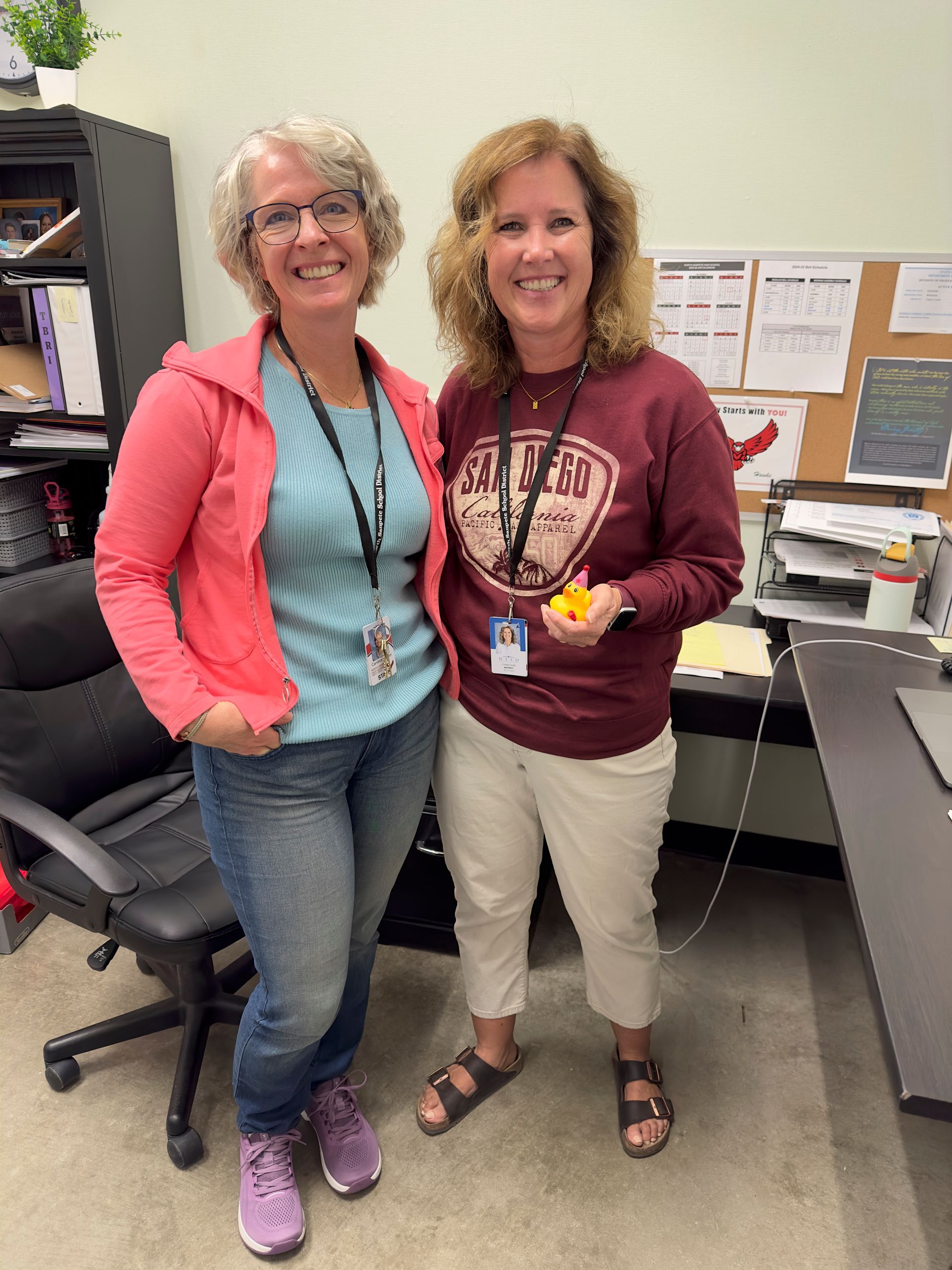 Two women are standing next to each other in an office.