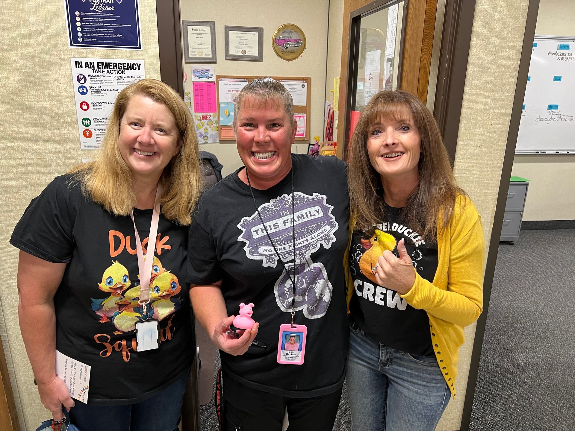 Three women are posing for a picture in a hallway.