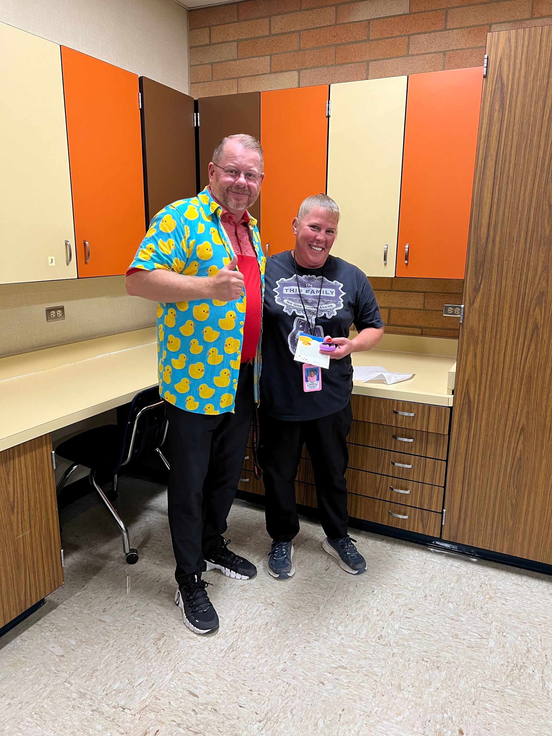 Two men are standing next to each other in a room with orange cabinets.