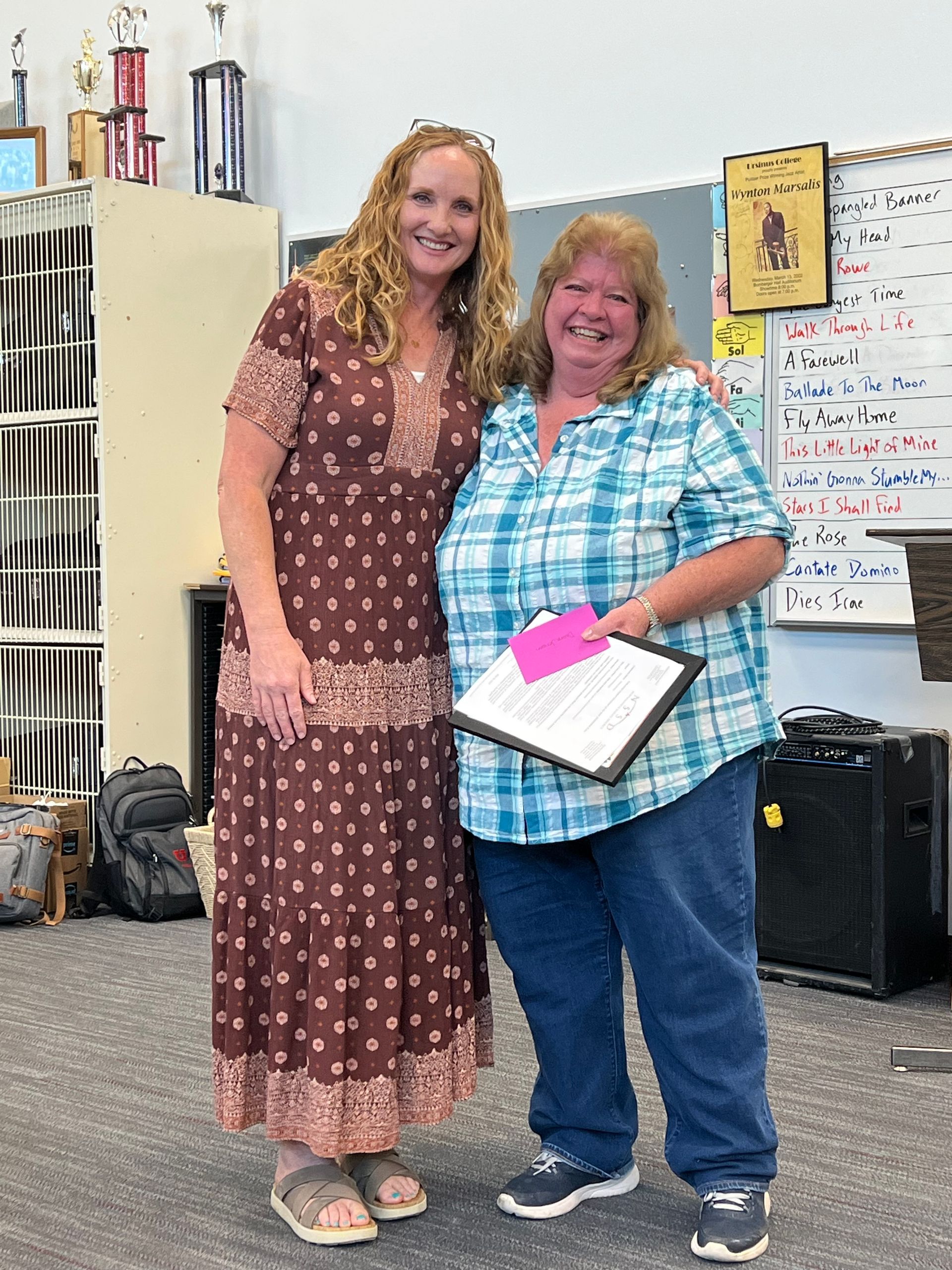 Two women are standing next to each other in a classroom holding a certificate.