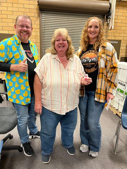 A man and two women are standing next to each other in a room.