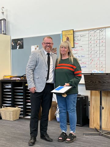 A man and a woman are standing next to each other in a classroom.