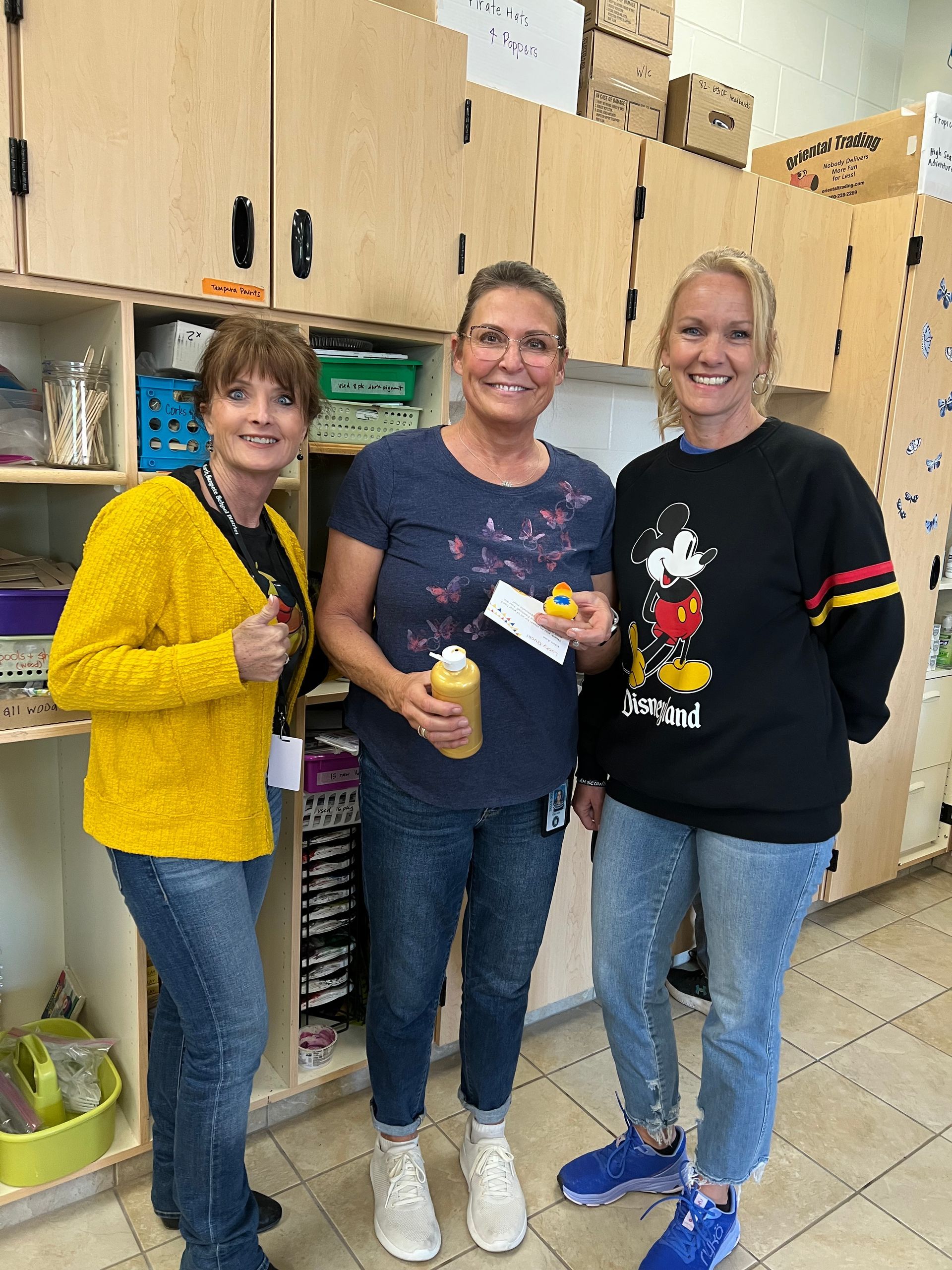 Three women are standing next to each other in a kitchen.