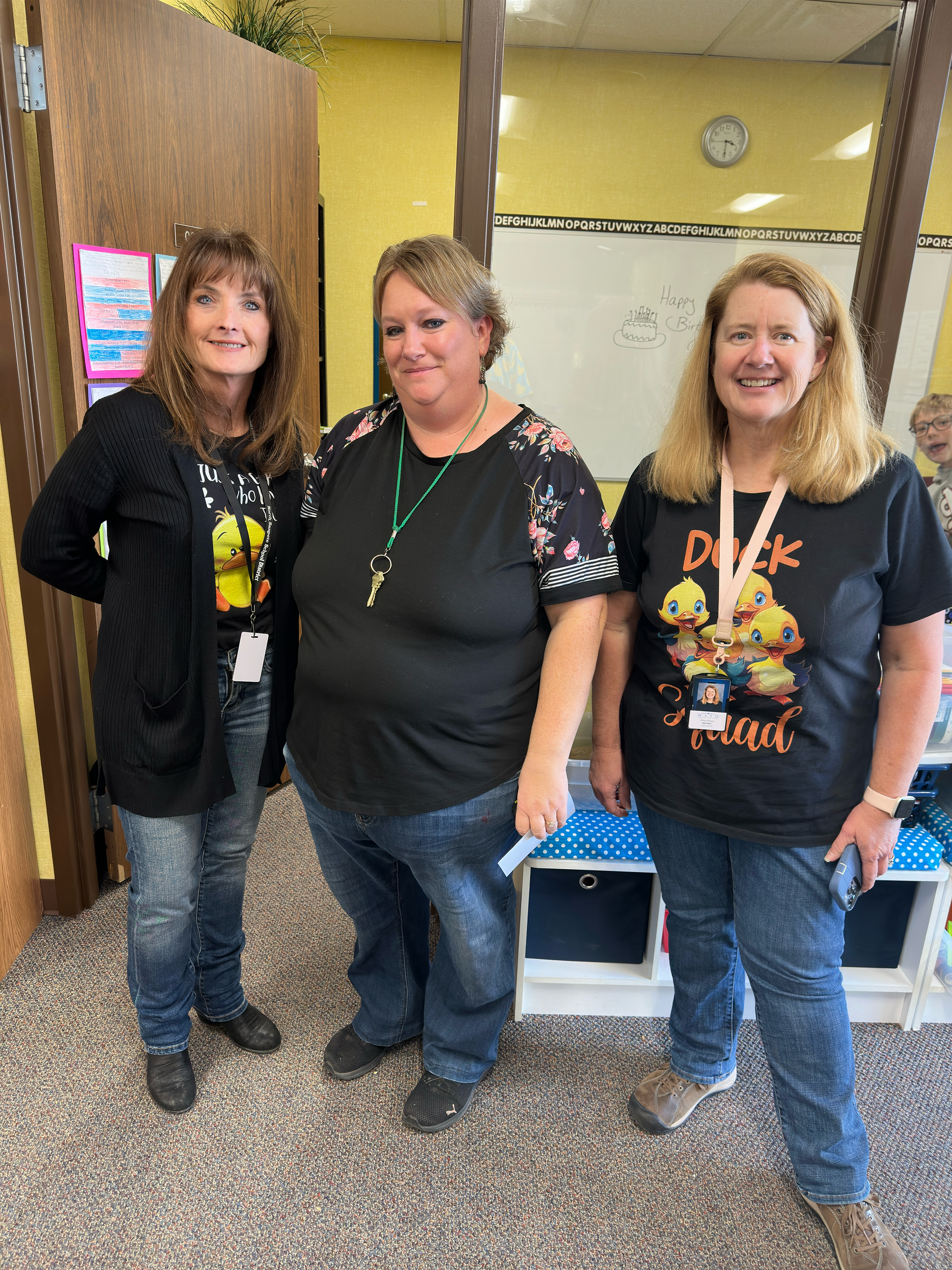 Three women are standing next to each other in a room.