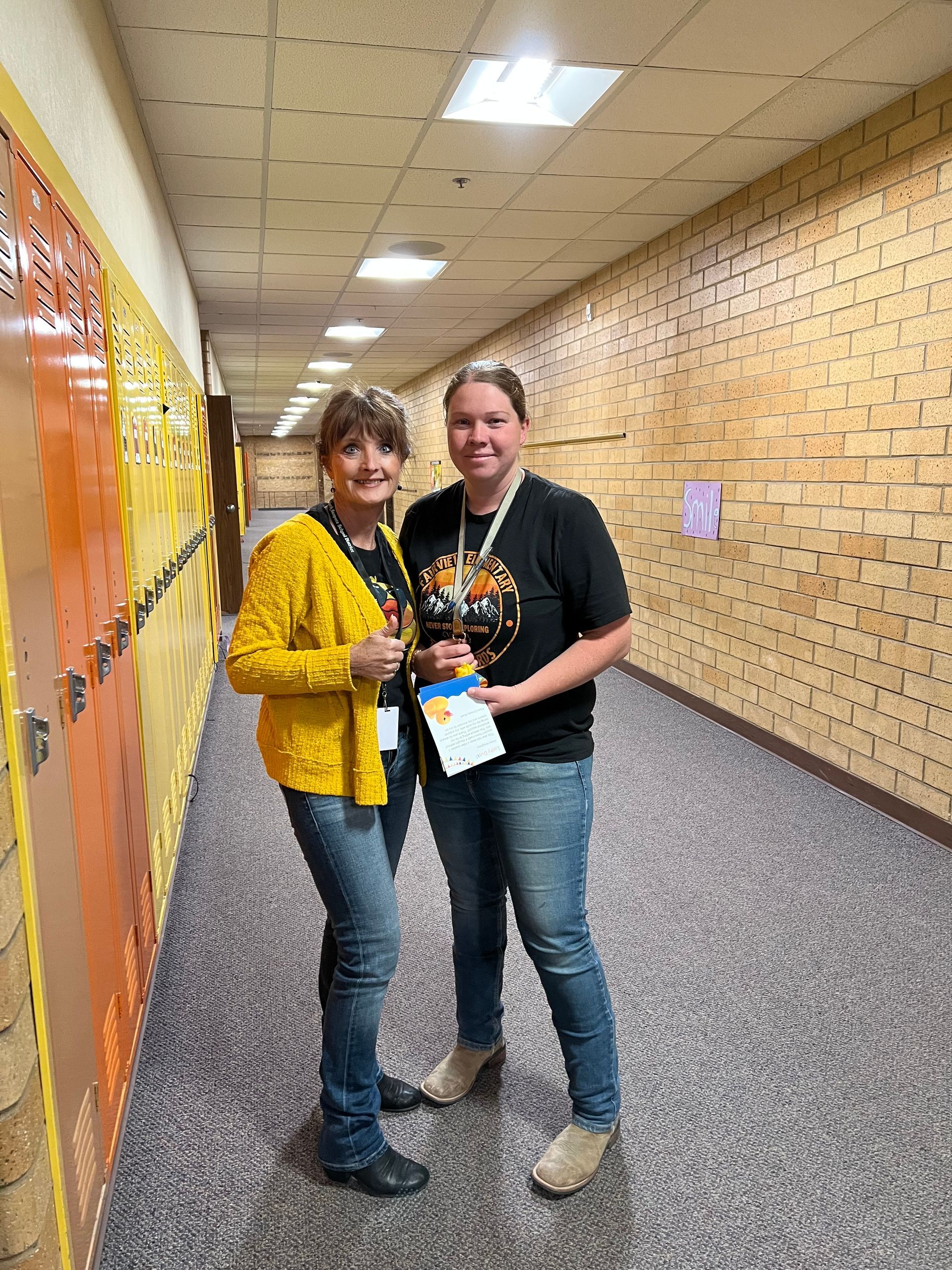 Two women are standing next to each other in a hallway.