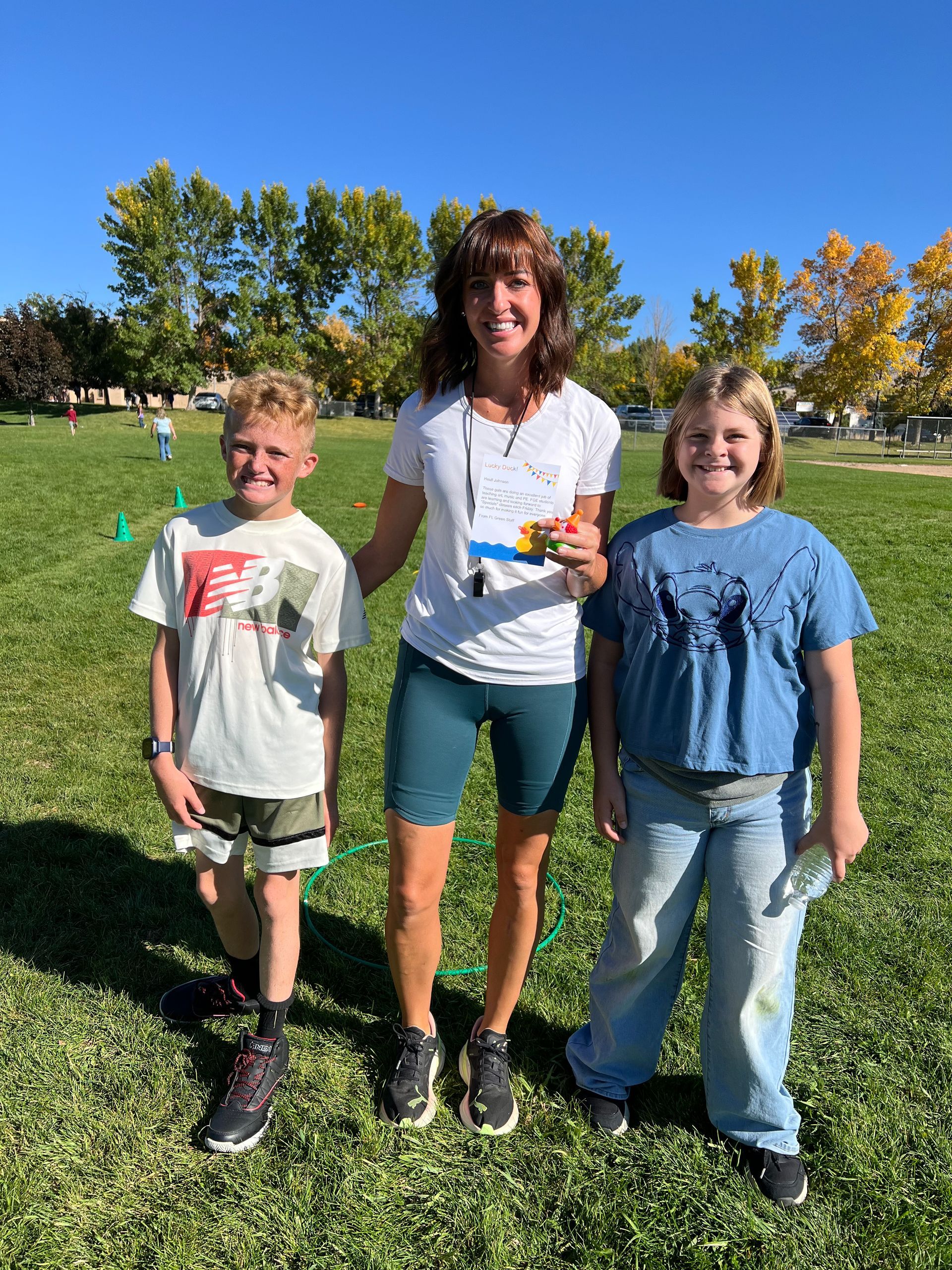 A woman and two children are standing in a grassy field.