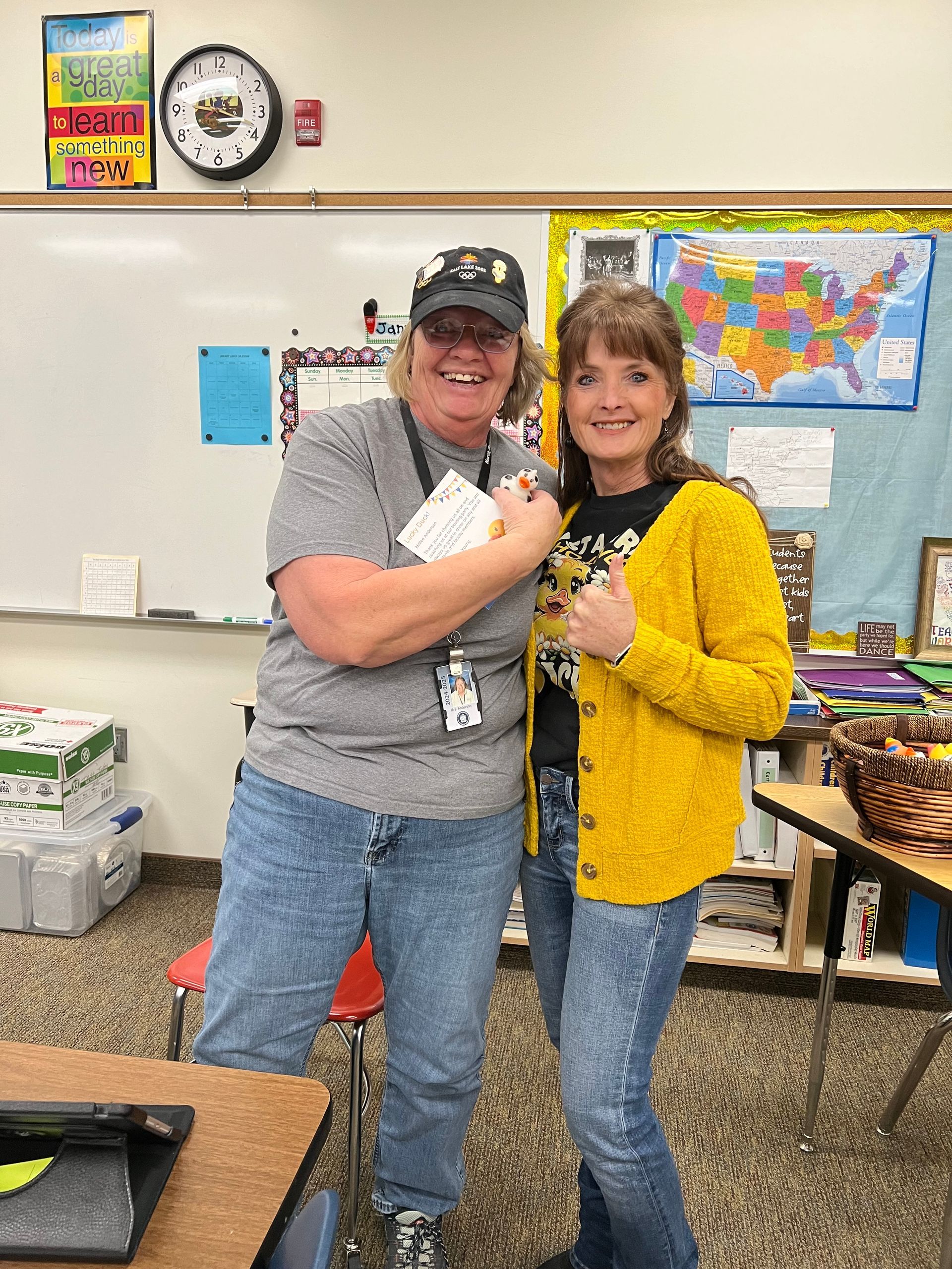 A man and a woman are standing next to each other in a classroom.