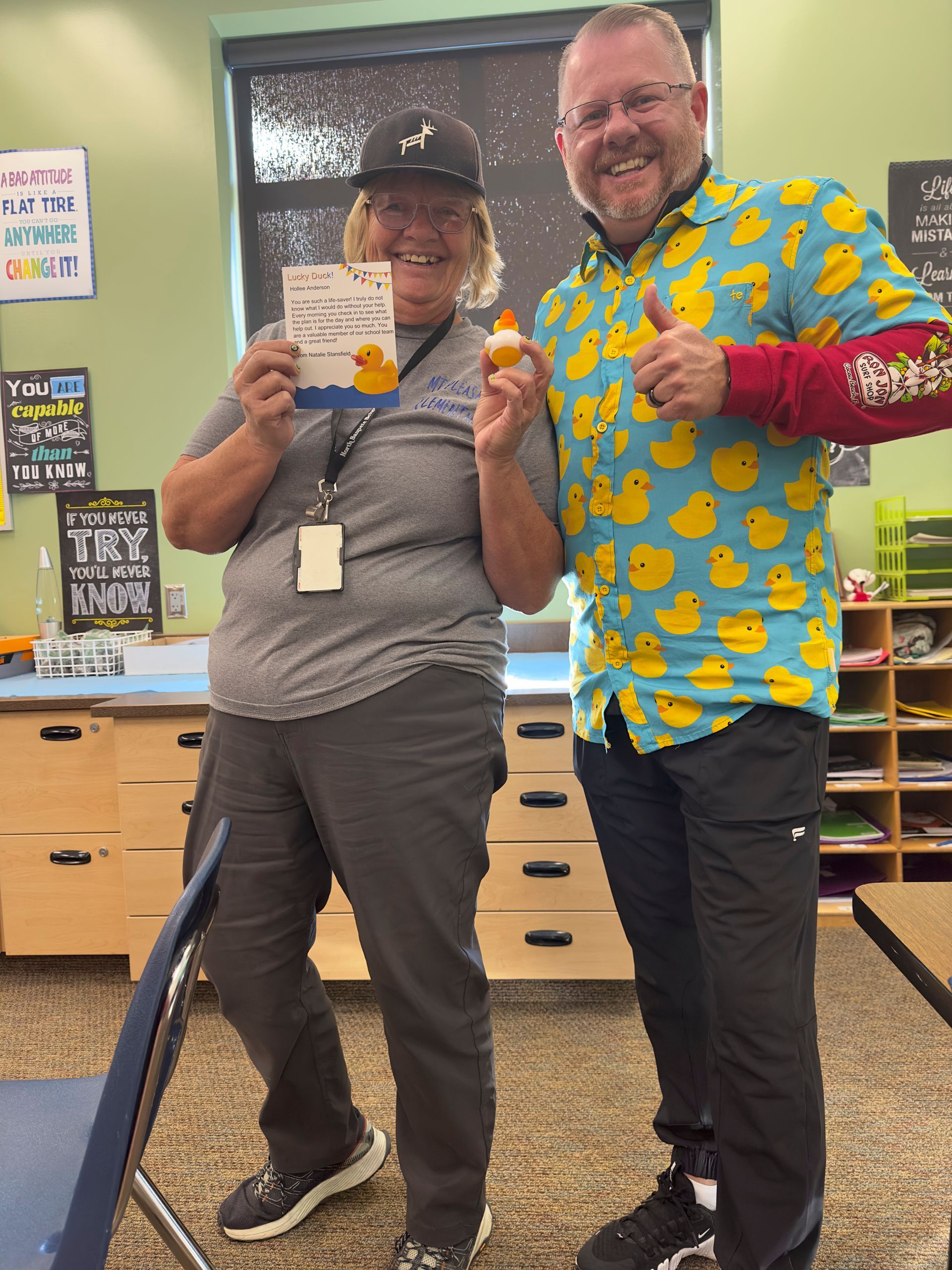 A man and a woman are posing for a picture in a classroom