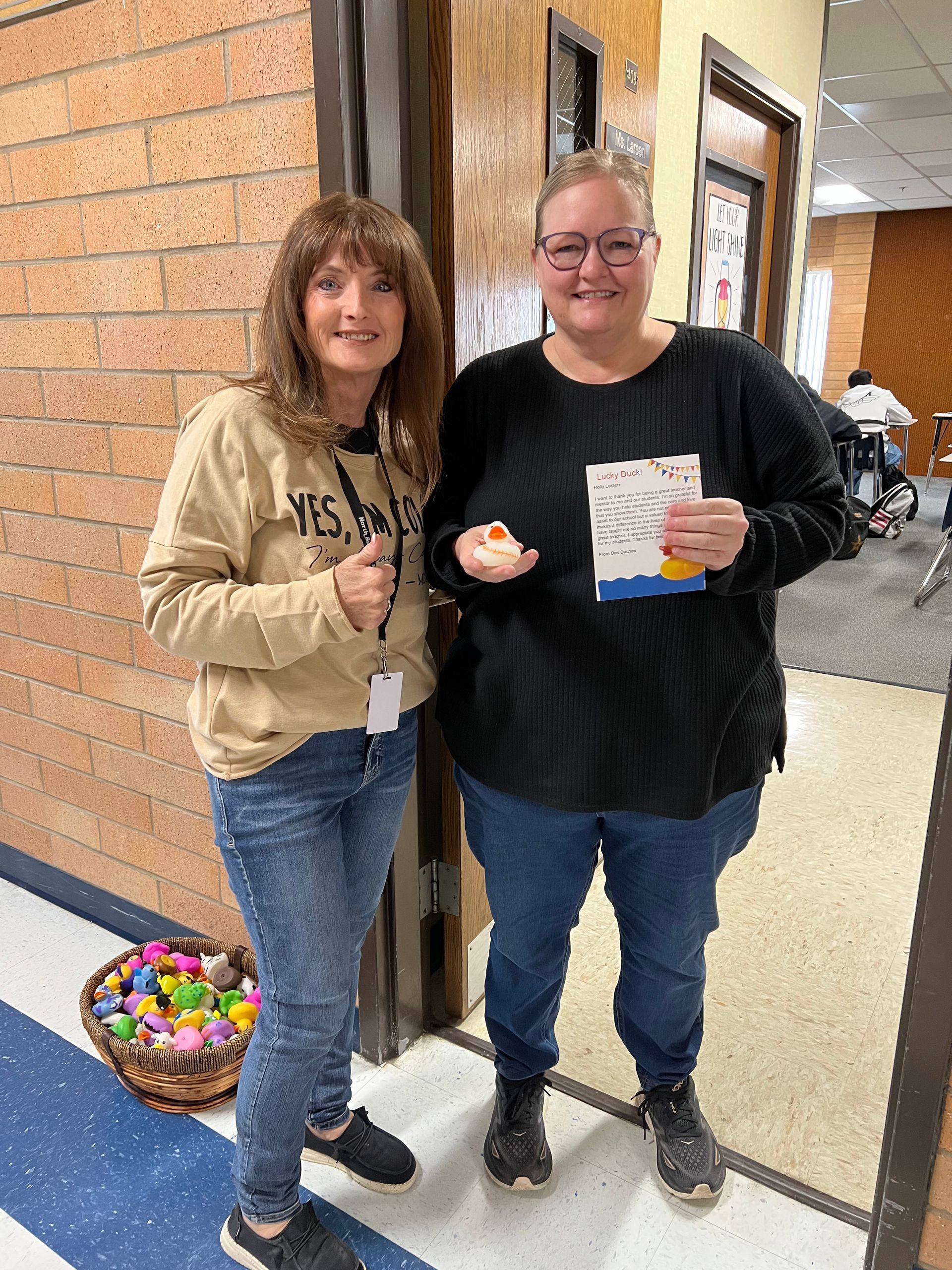 Two women are standing next to each other in a hallway.