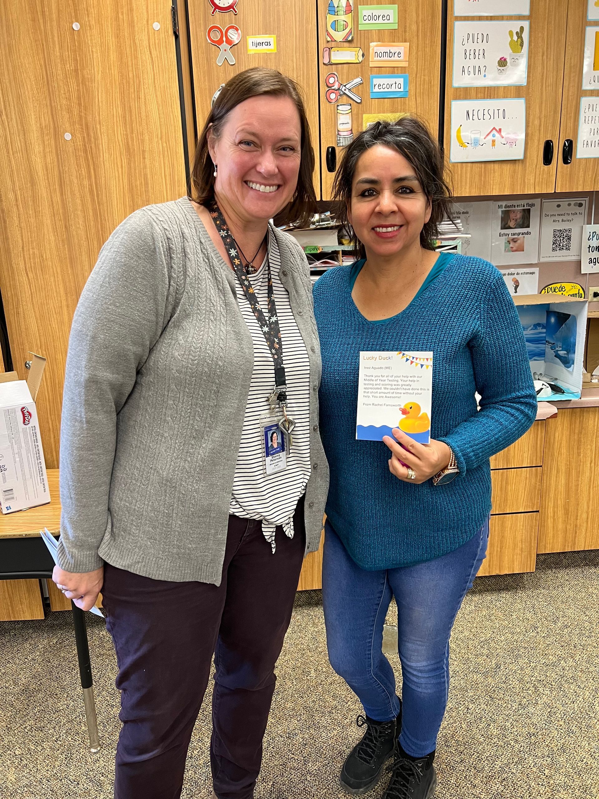 Two women are standing next to each other and one is holding a book.