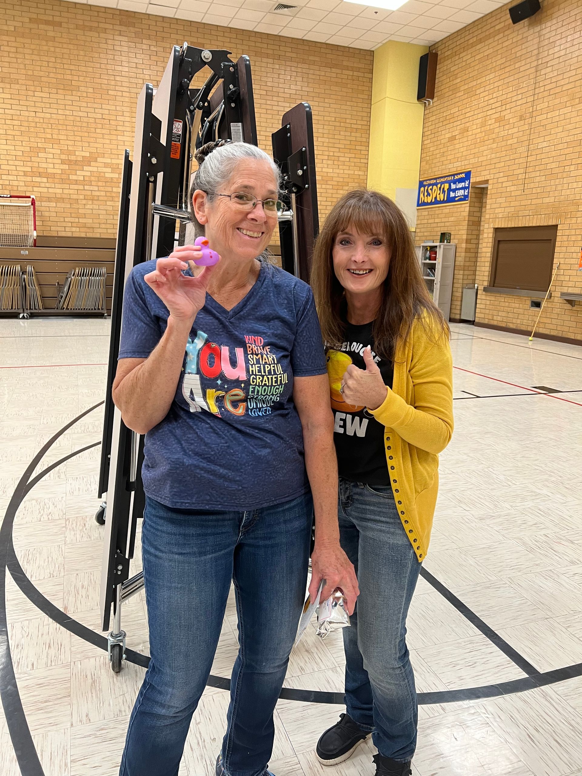 Two women are posing for a picture in a gym.