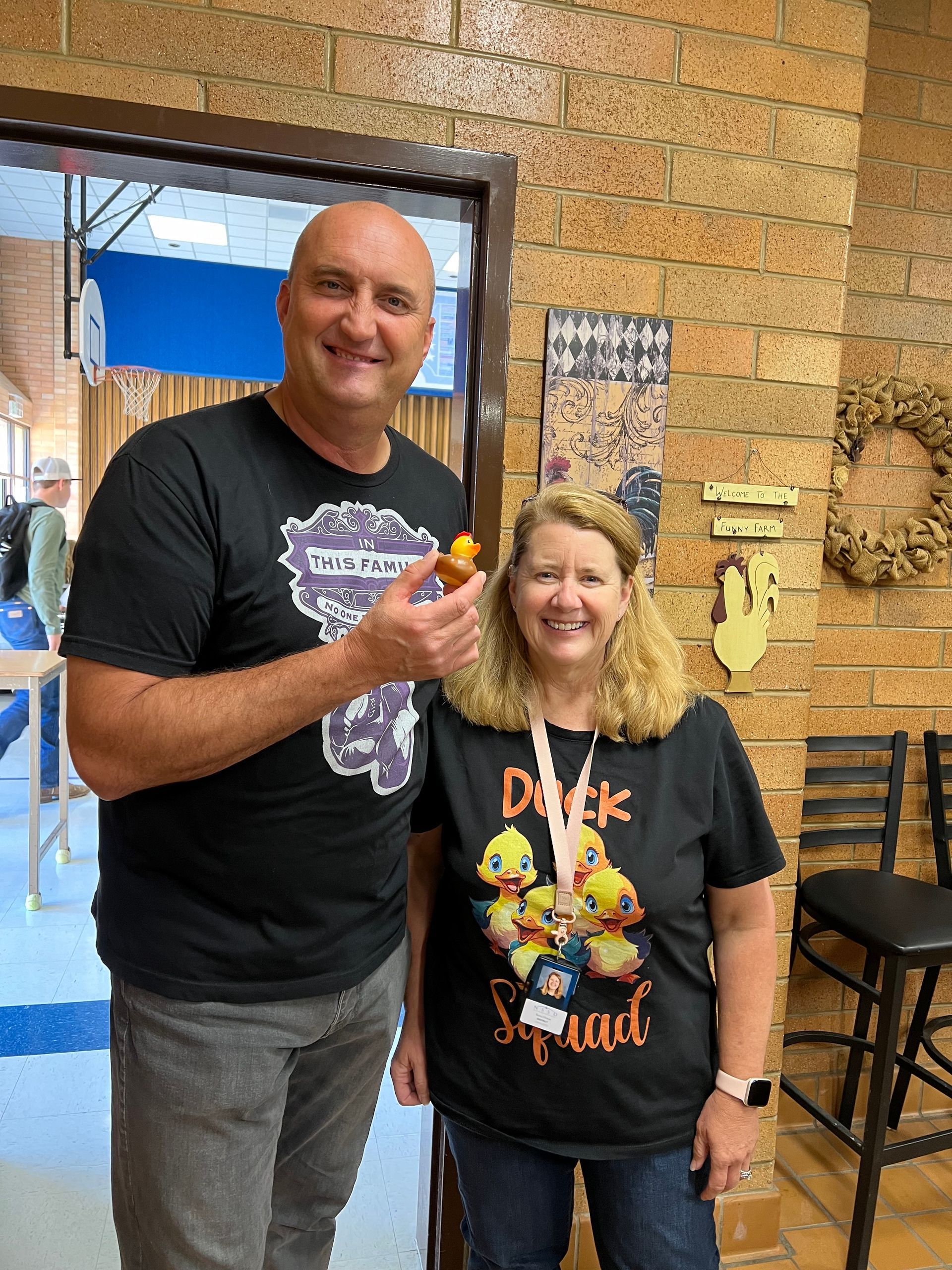 A man and a woman are standing next to each other in front of a brick wall.