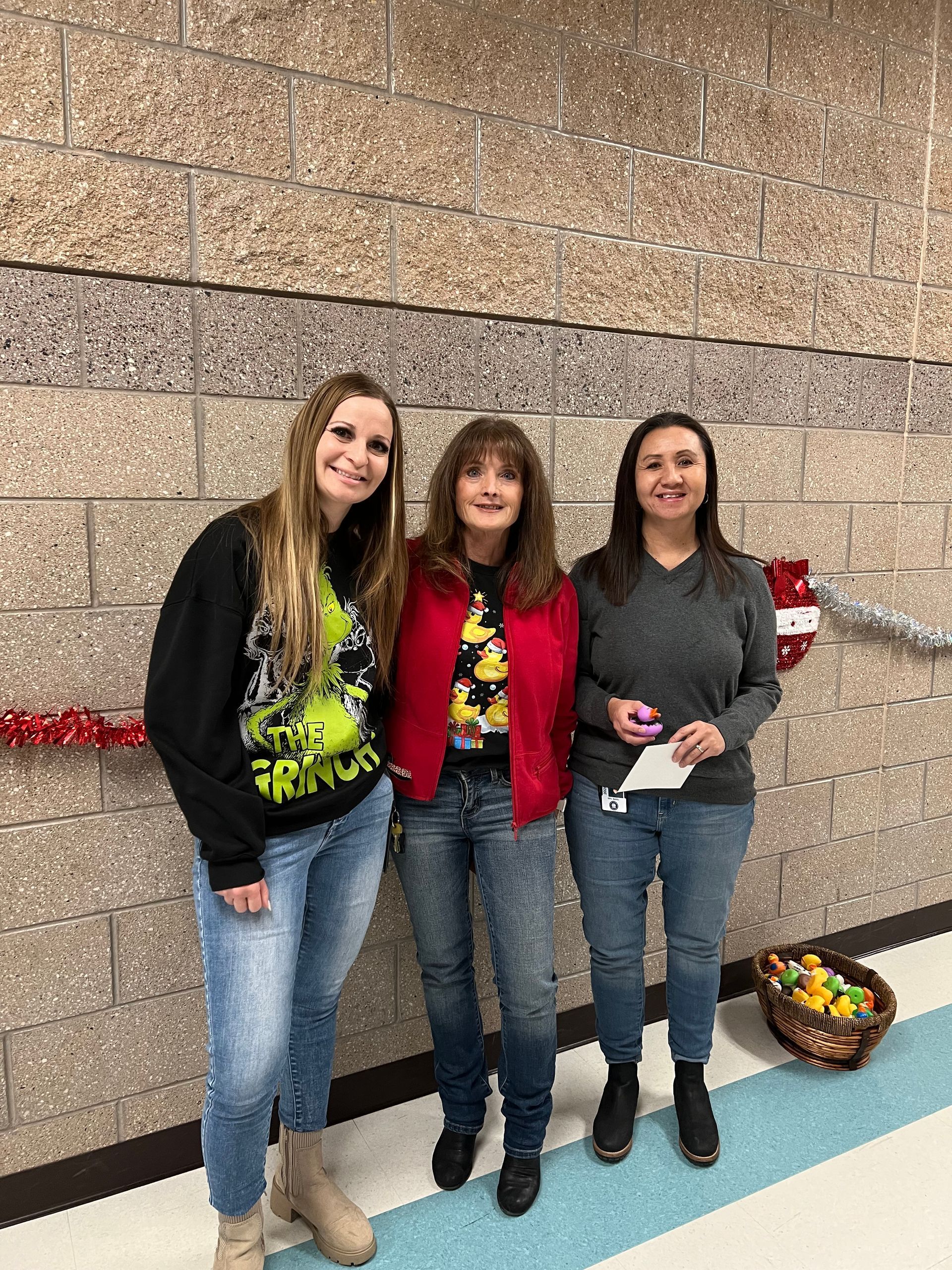 Three women are standing next to each other in front of a brick wall.