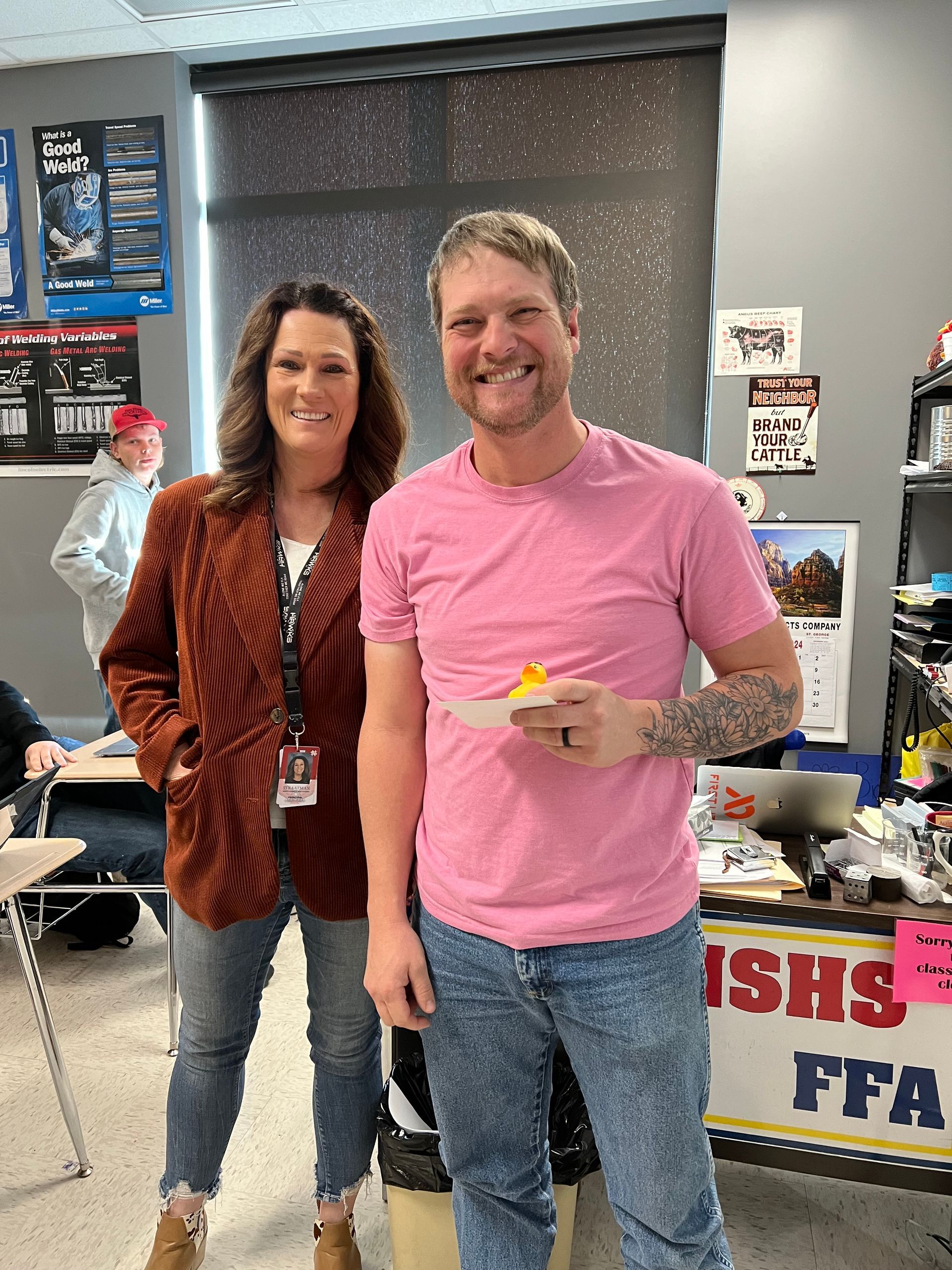 A man in a pink shirt is standing next to a woman in a brown jacket.