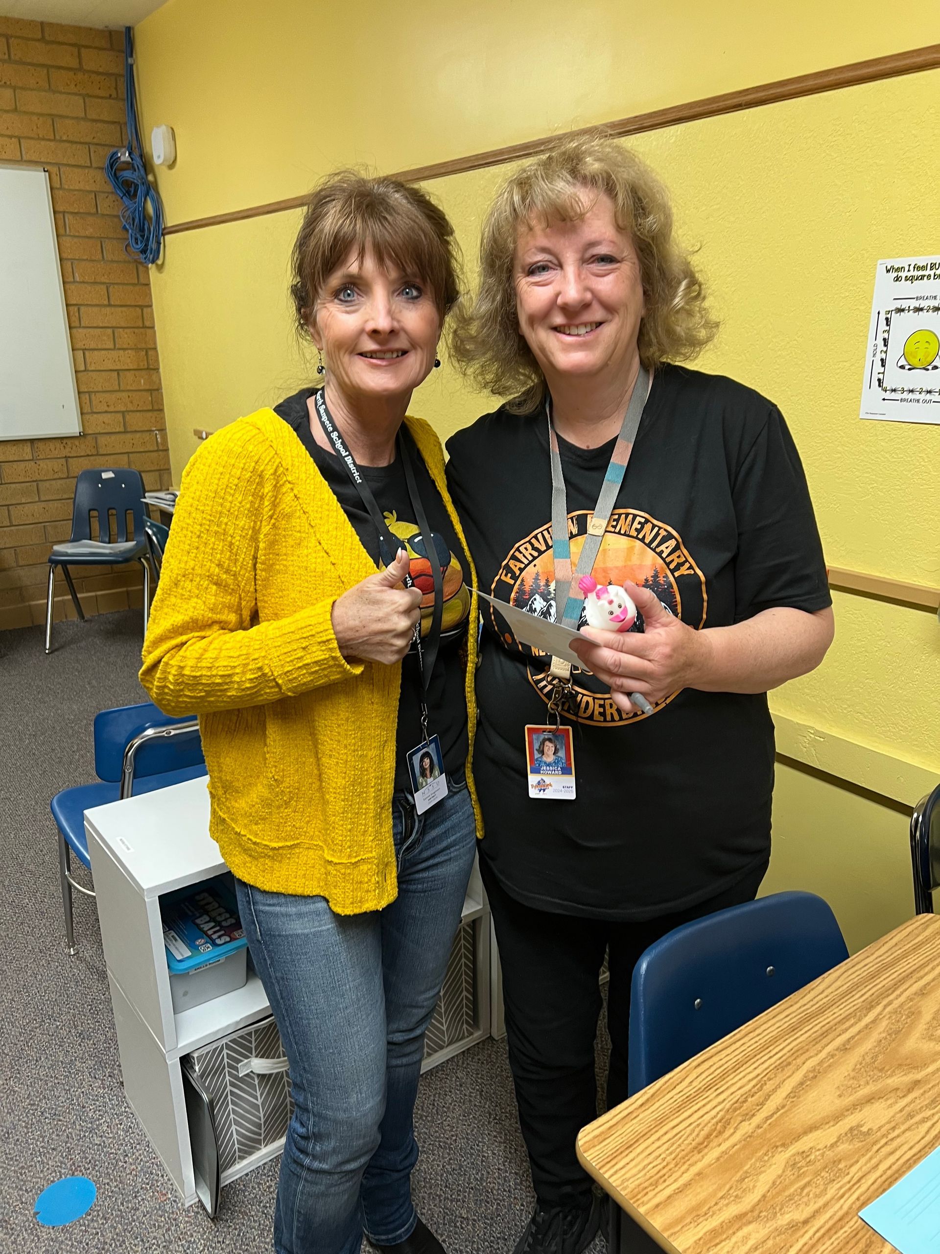 Two women are standing next to each other in a classroom.