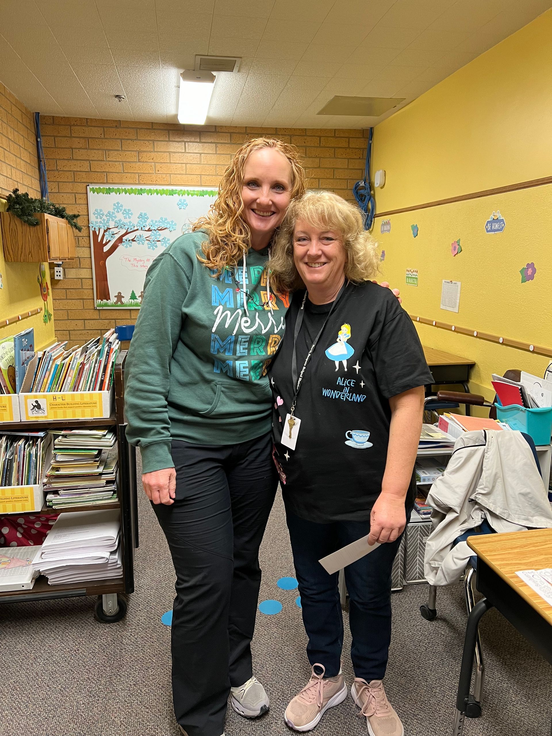 Two women are posing for a picture in a classroom.