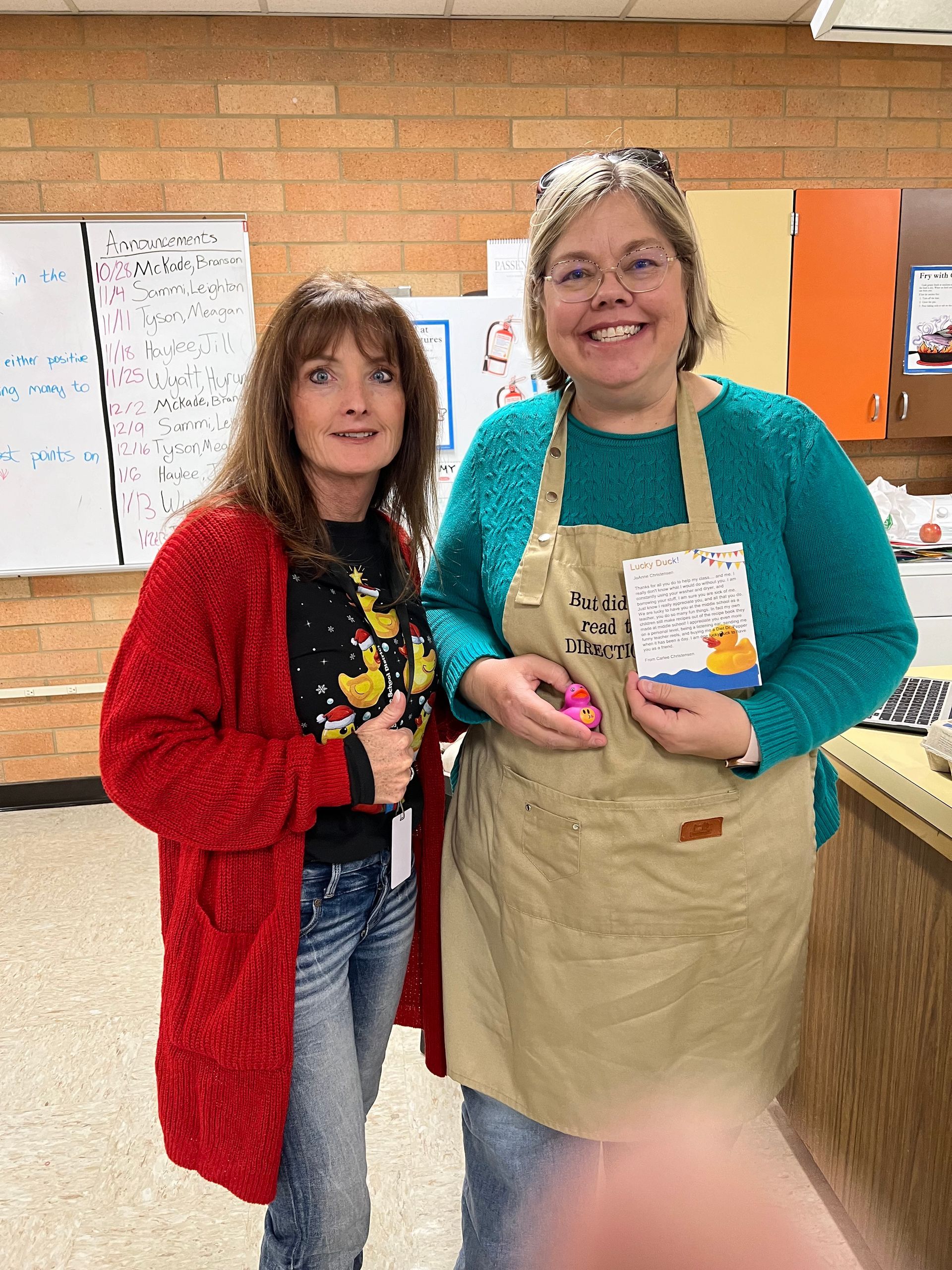 Two women in aprons are standing next to each other in a kitchen.