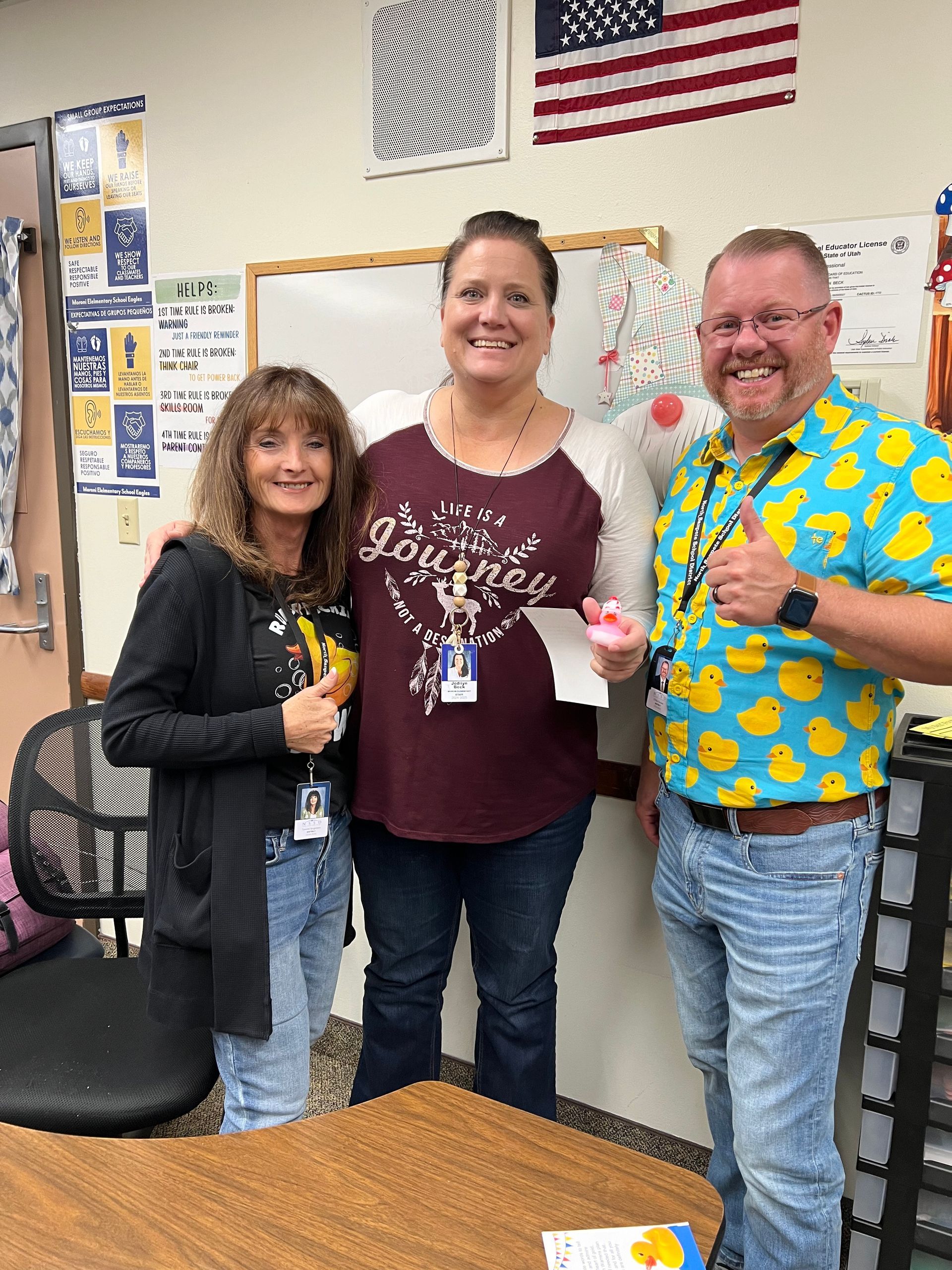 Three people are posing for a picture in a classroom.