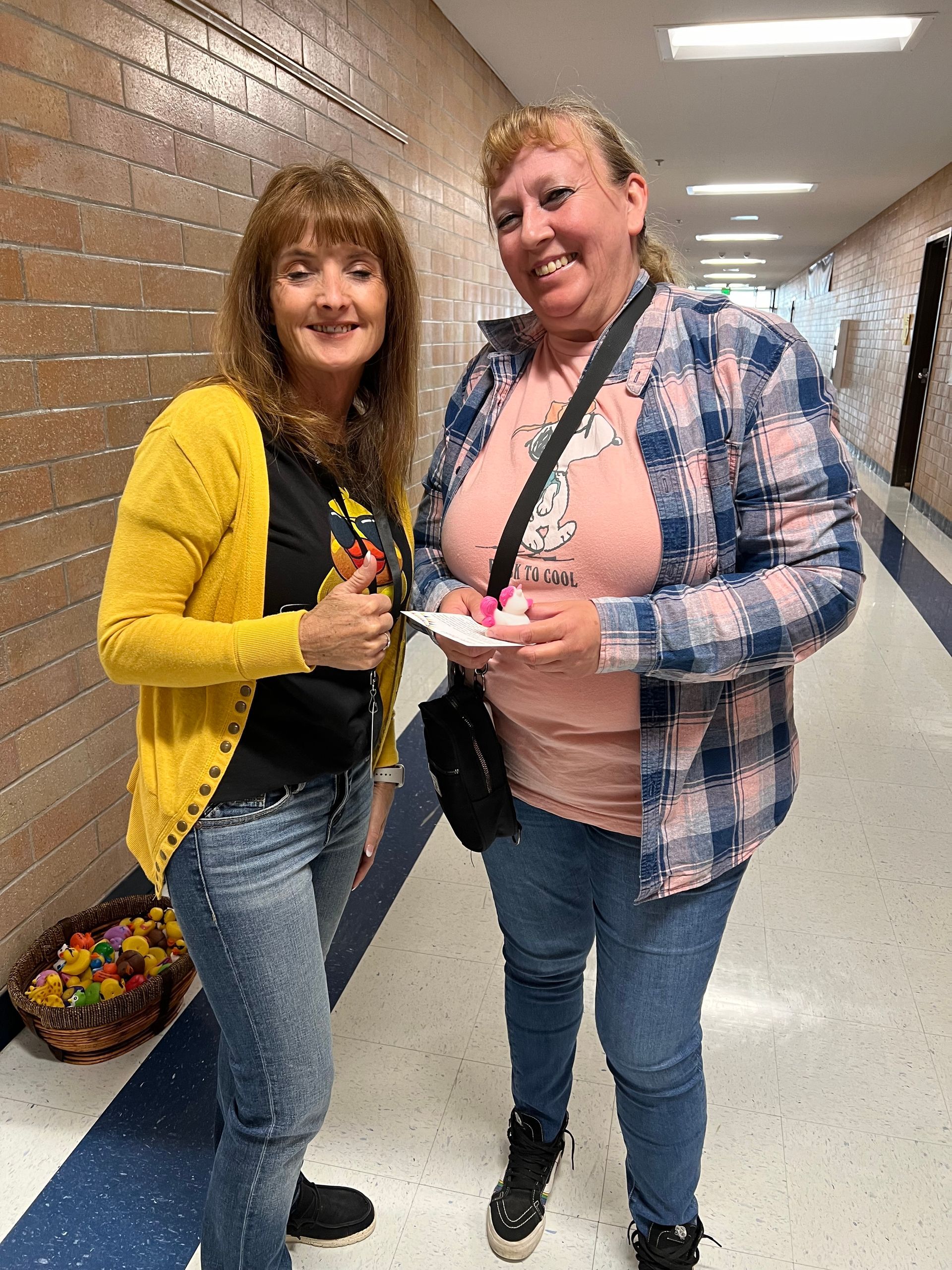 Two women are standing next to each other in a hallway.