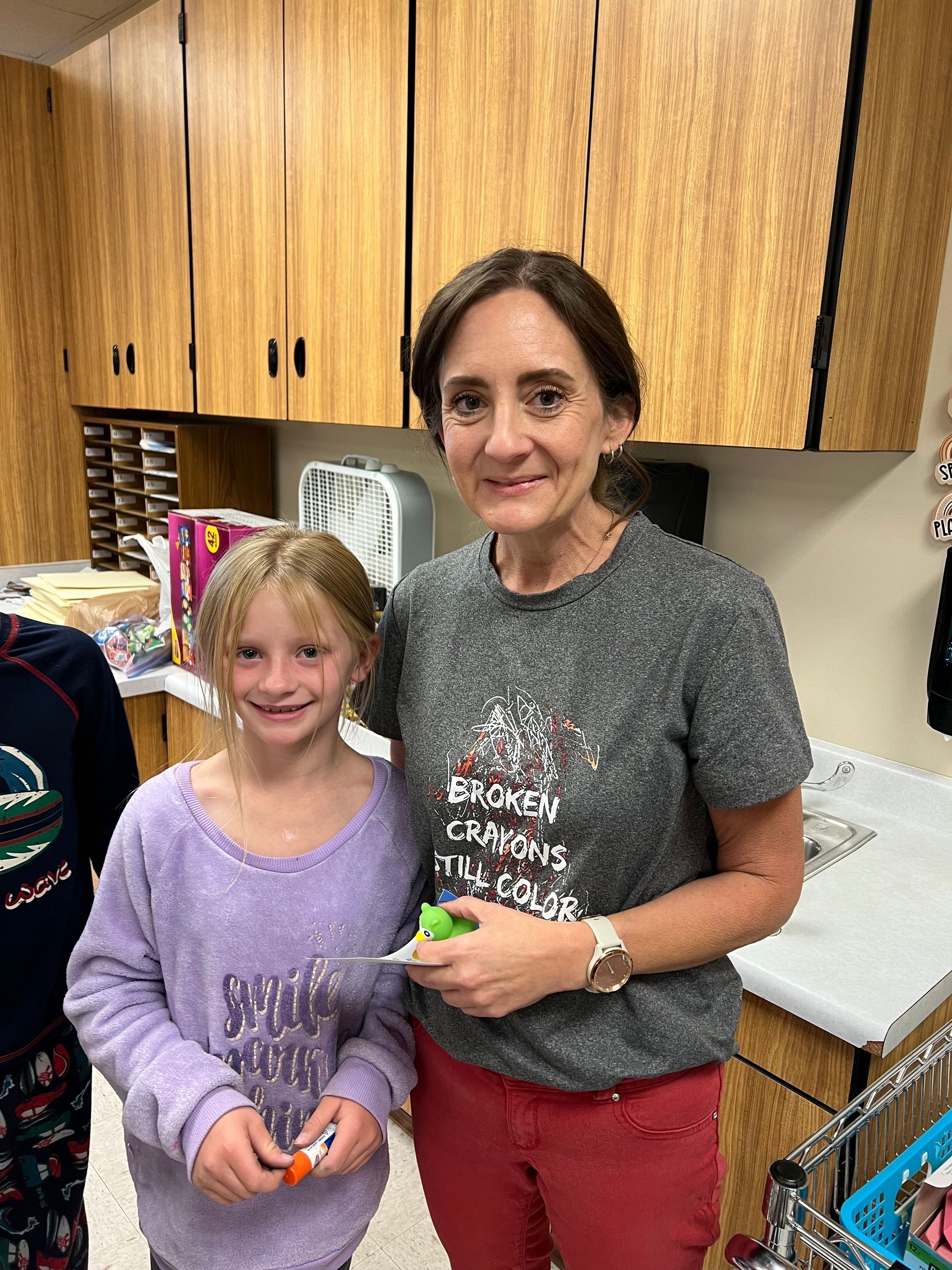 A woman and a little girl are posing for a picture in a kitchen.