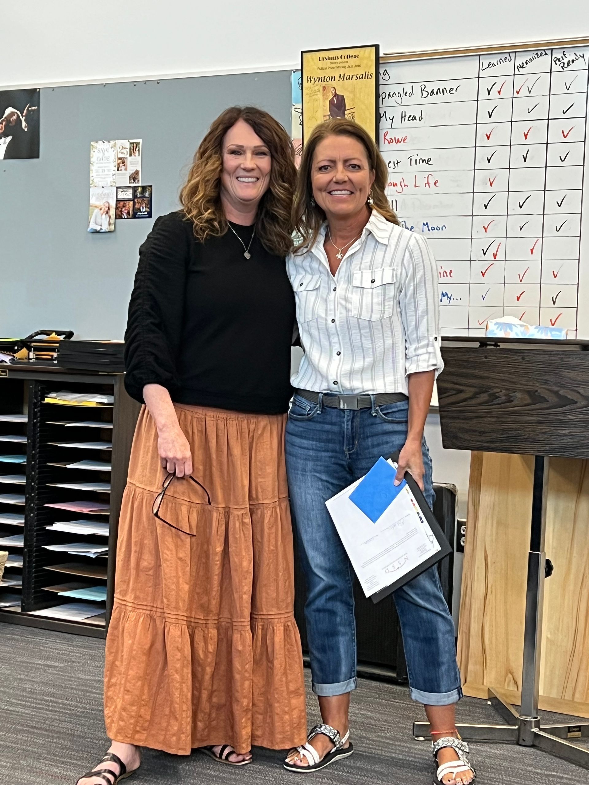 Two women are standing next to each other in a classroom.