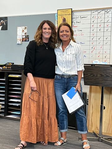 Two women are standing next to each other in a classroom.
