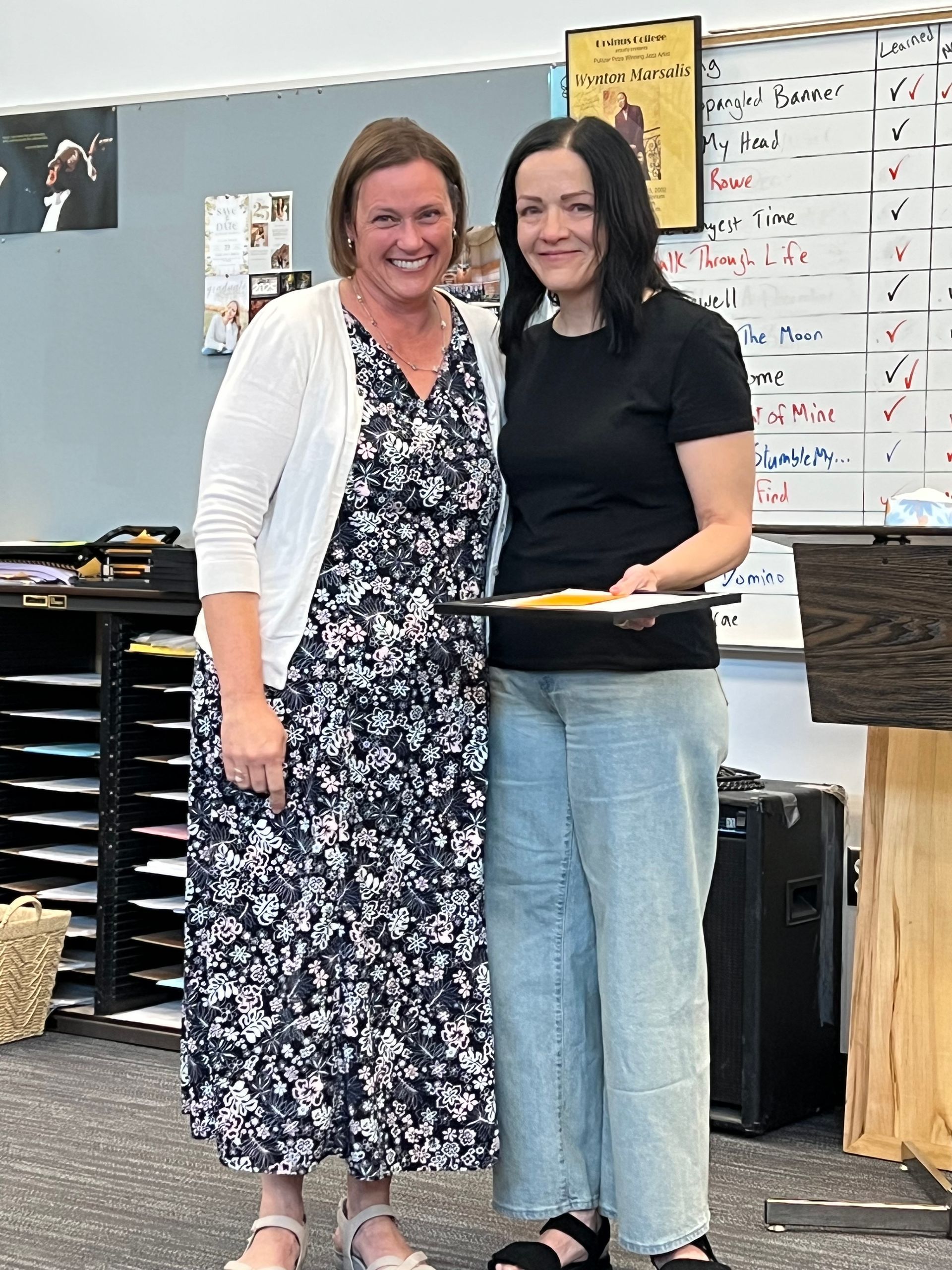Two women are standing next to each other in a classroom.