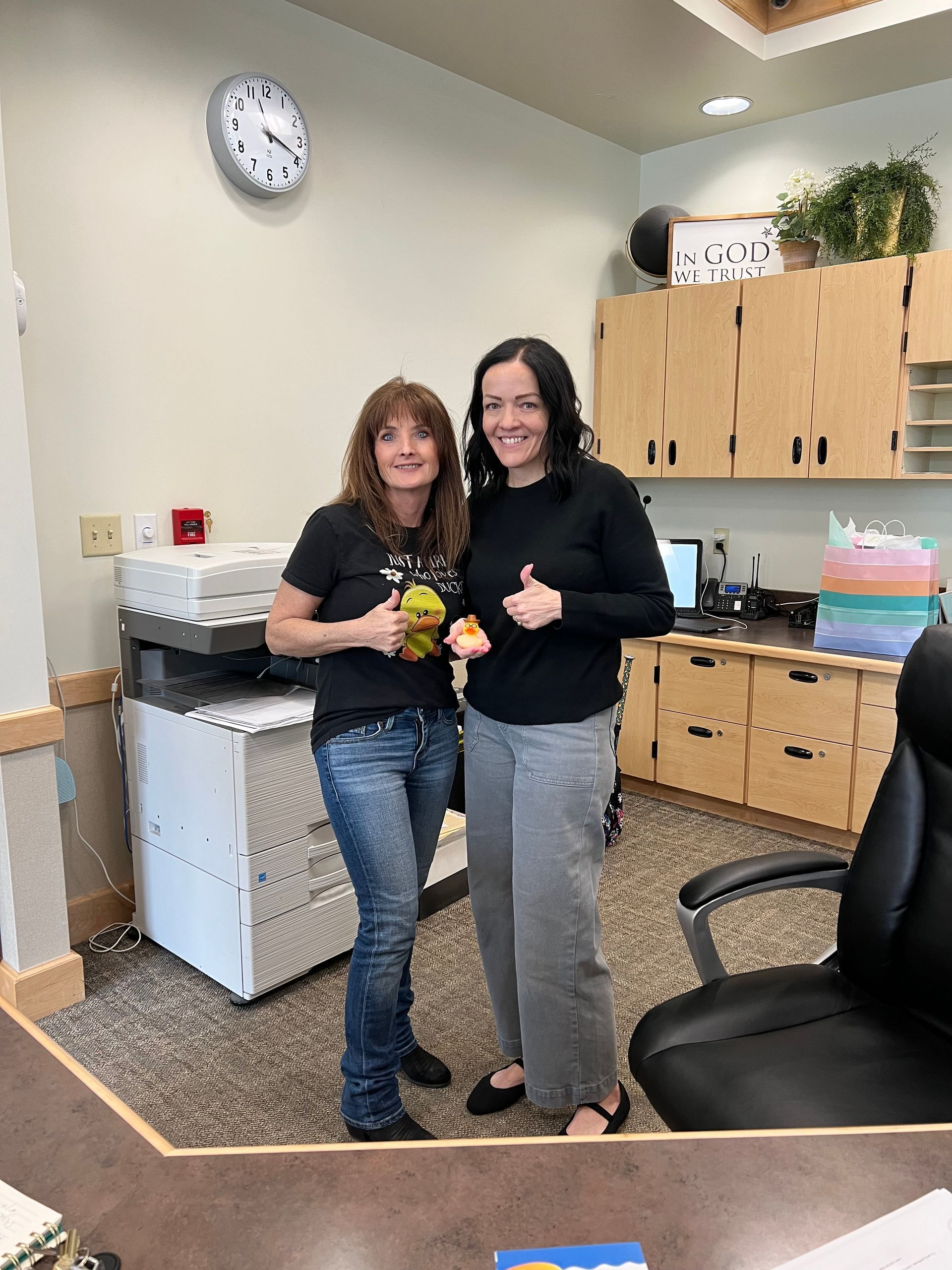Two women are standing next to each other in an office.