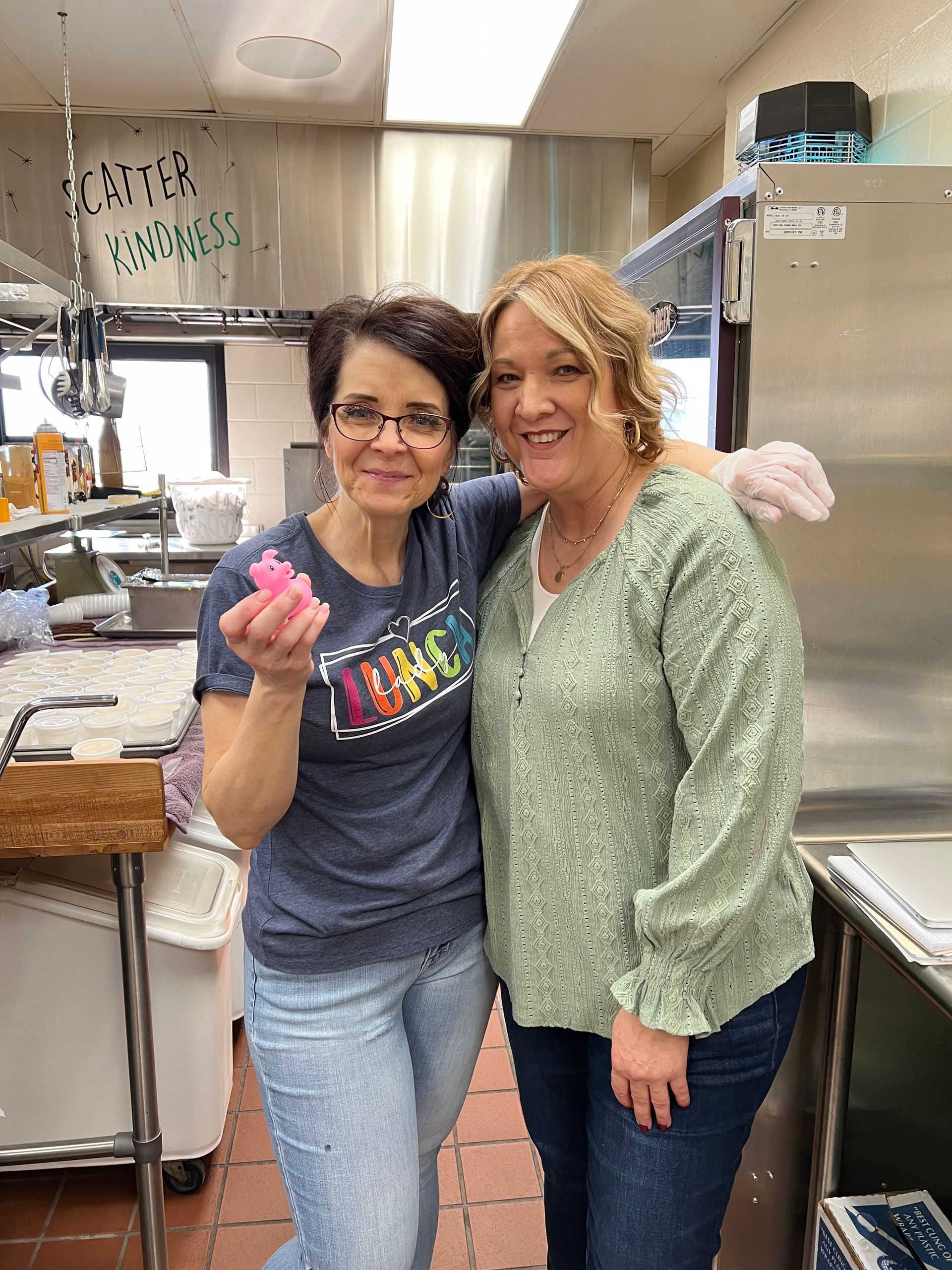 Two women are posing for a picture in a kitchen.