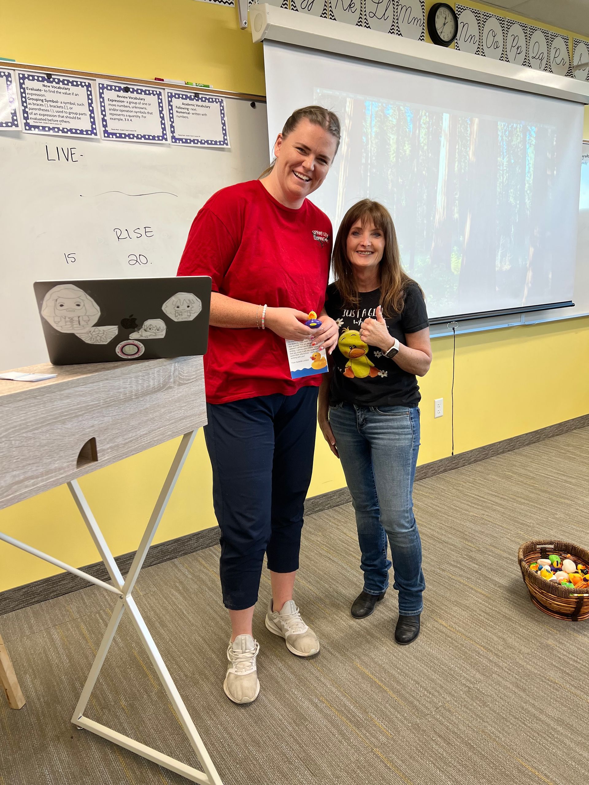Two women are standing next to each other in a classroom.