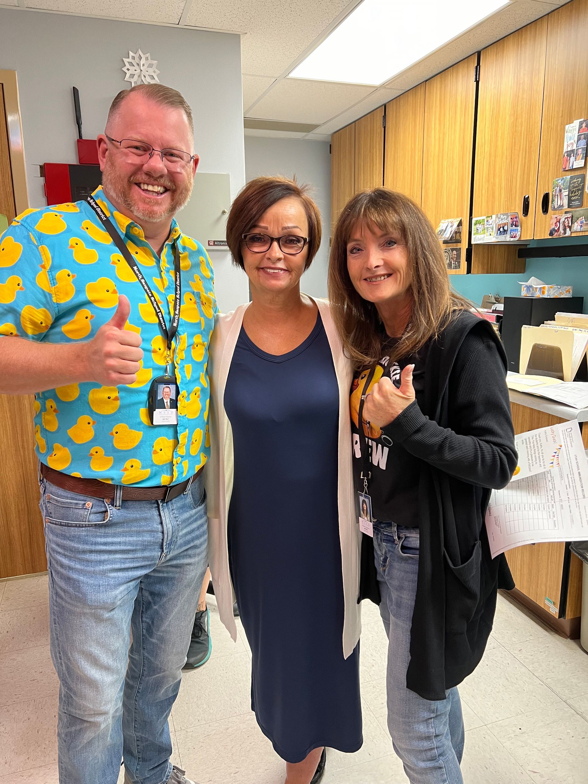 A man in a duck shirt is posing for a picture with two women.