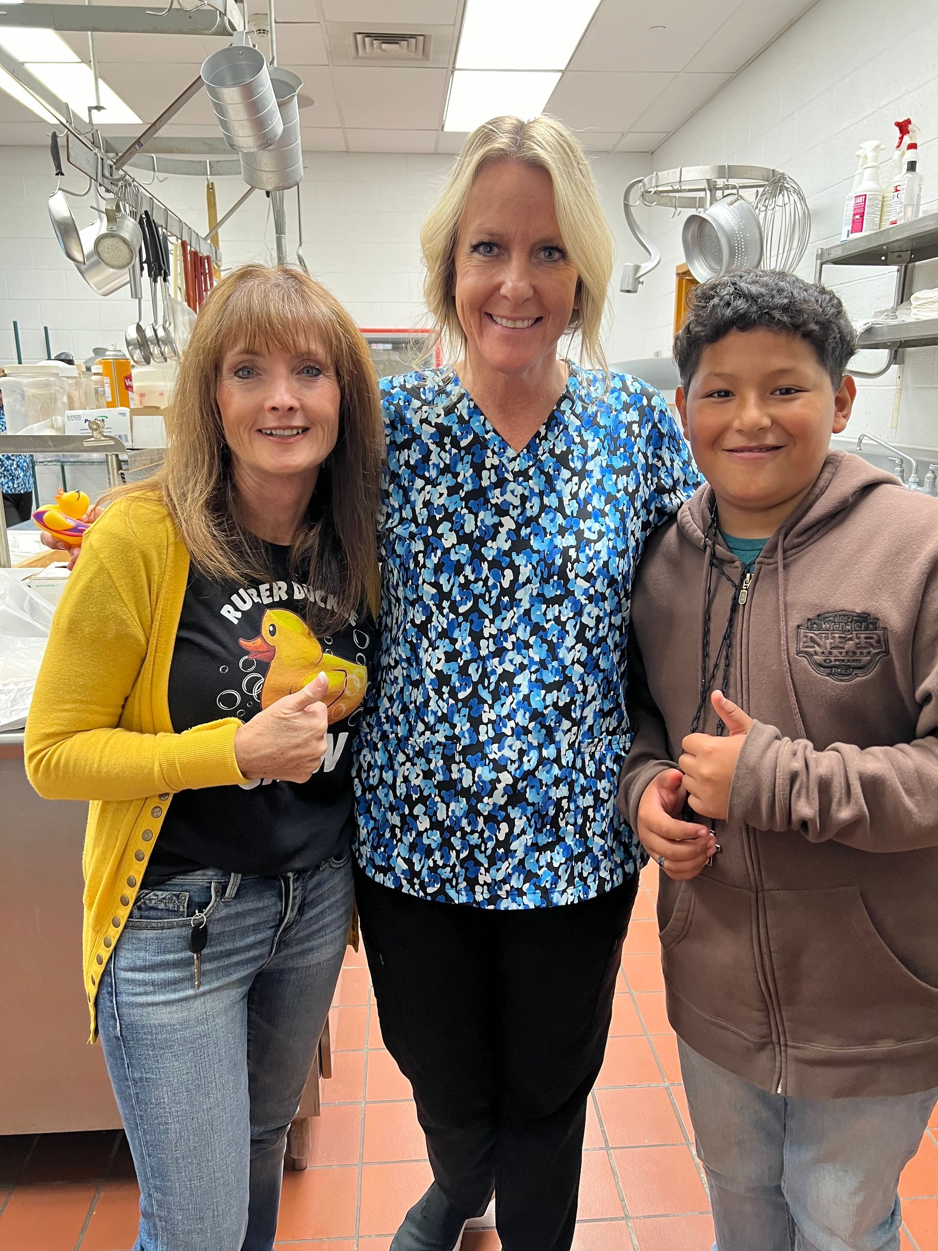 Two women and a boy are posing for a picture in a kitchen