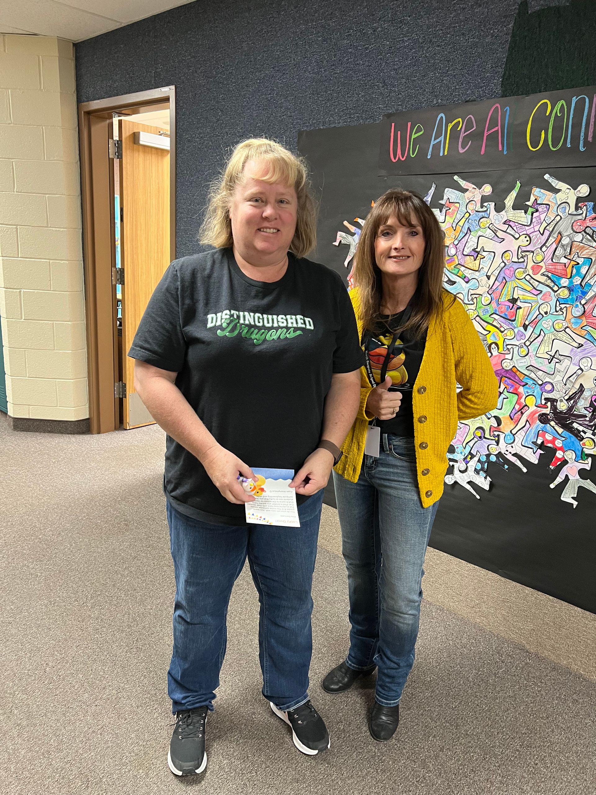 Two women are standing next to each other in a hallway.