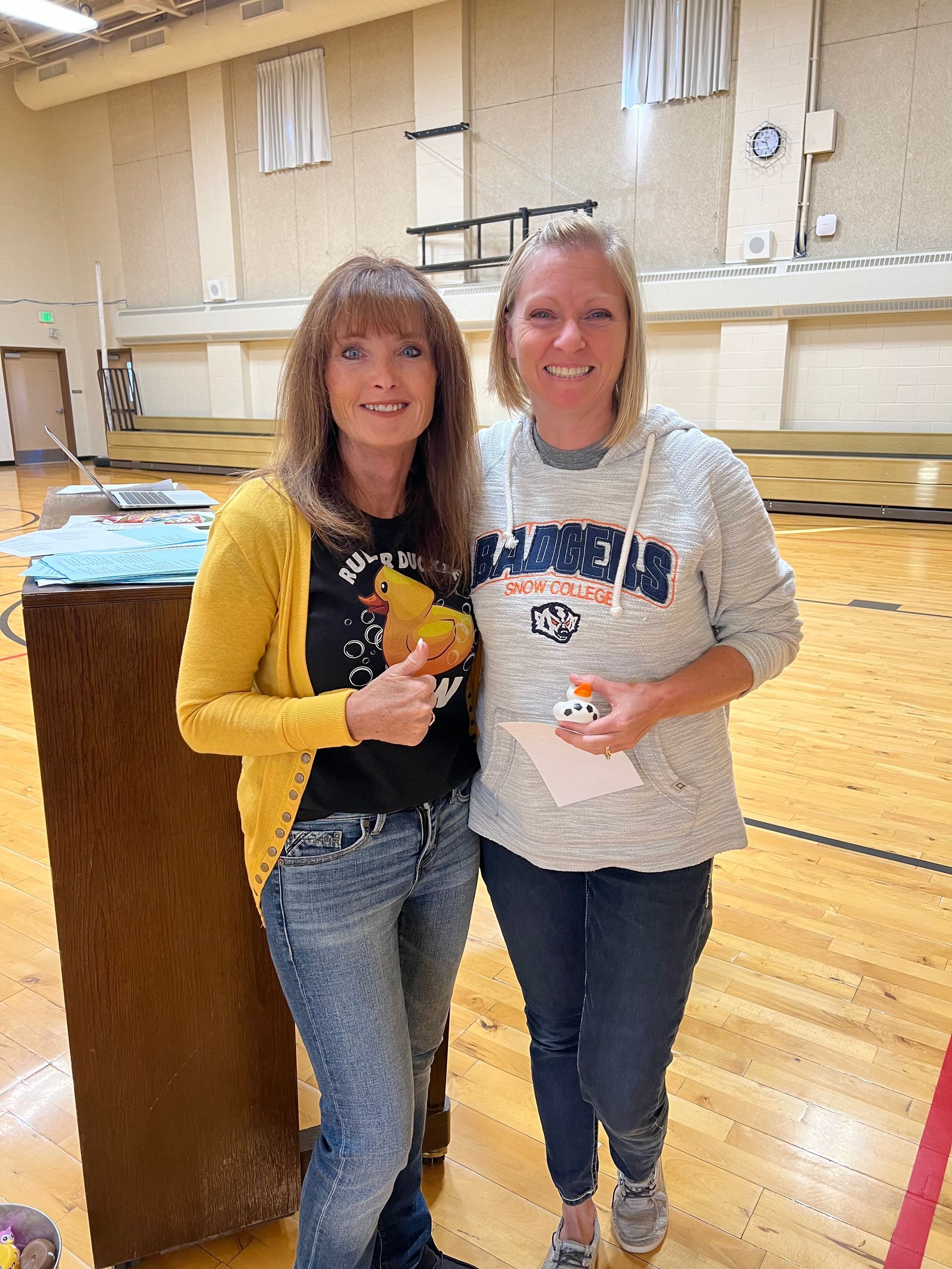 Two women are posing for a picture in a gym.