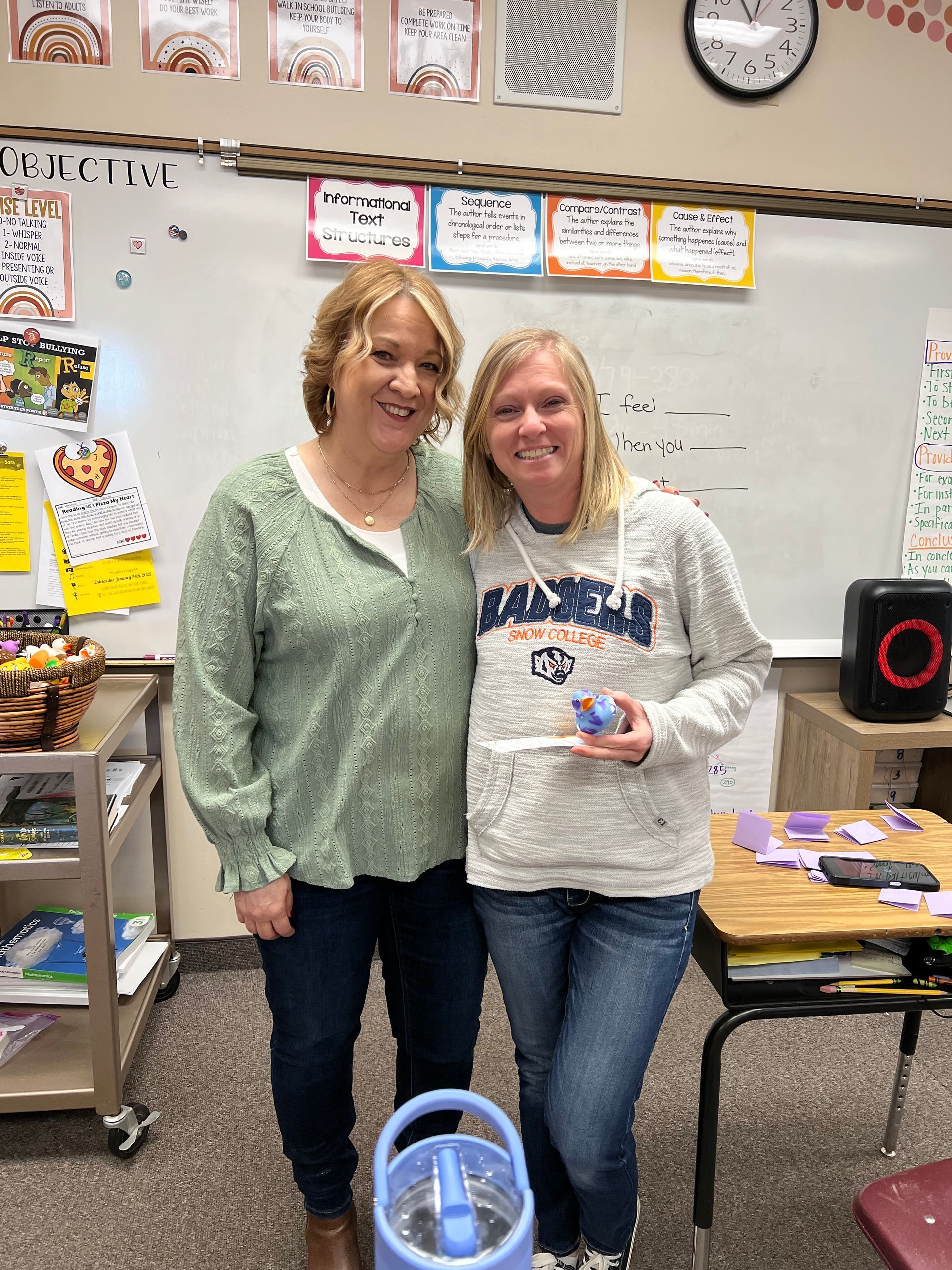 Two women are standing next to each other in a classroom.