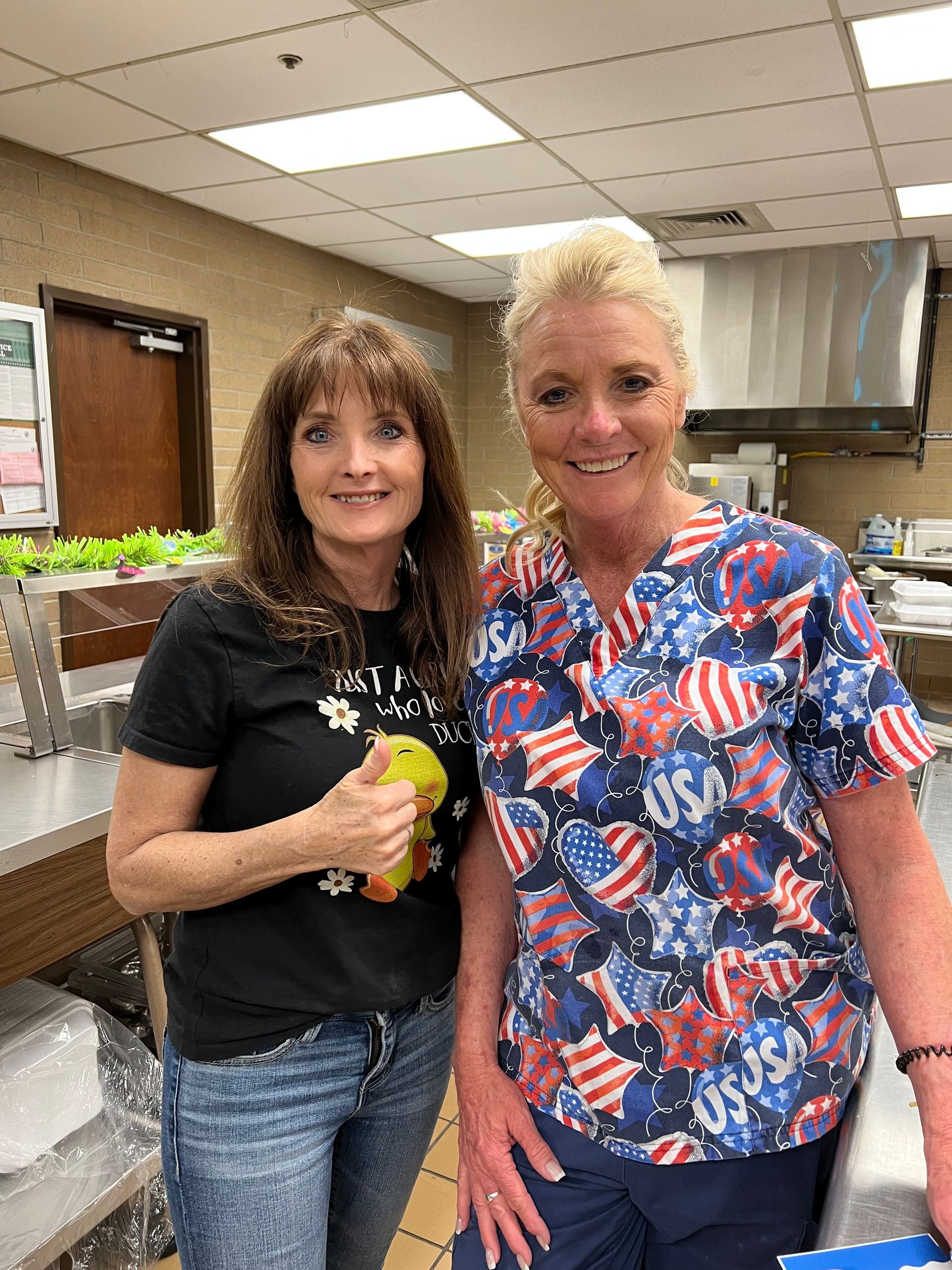 Two women are standing next to each other in a kitchen.