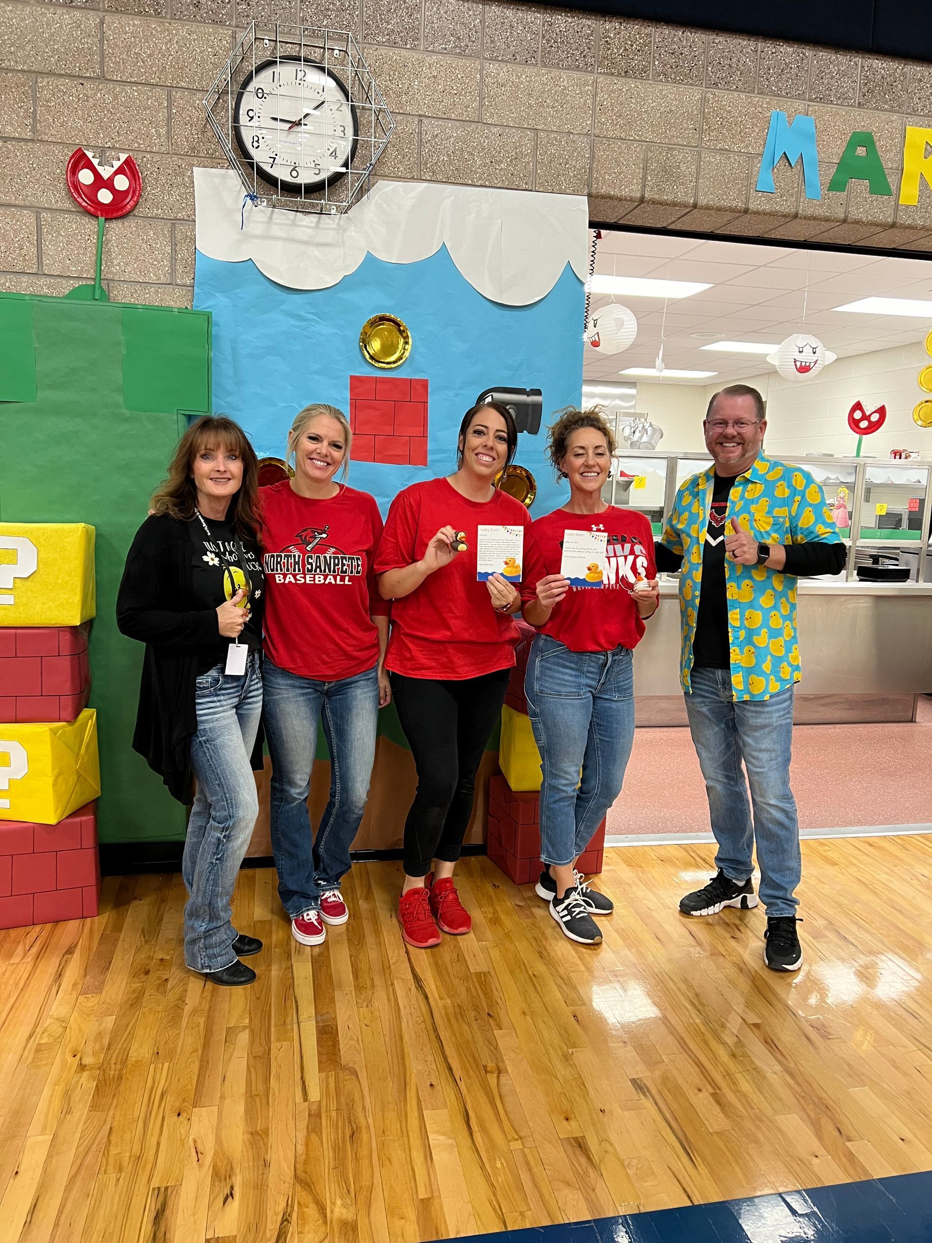 A group of people are posing for a picture in front of a mario wall.