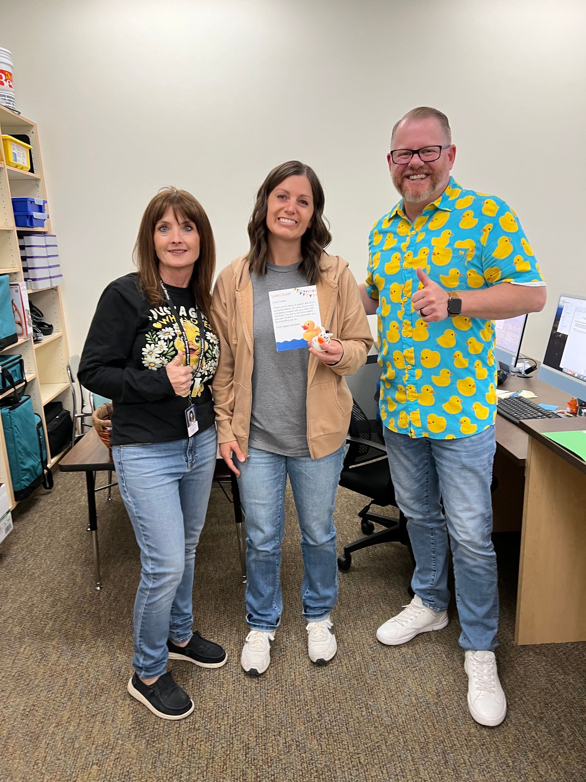 Three people are standing next to each other in an office.