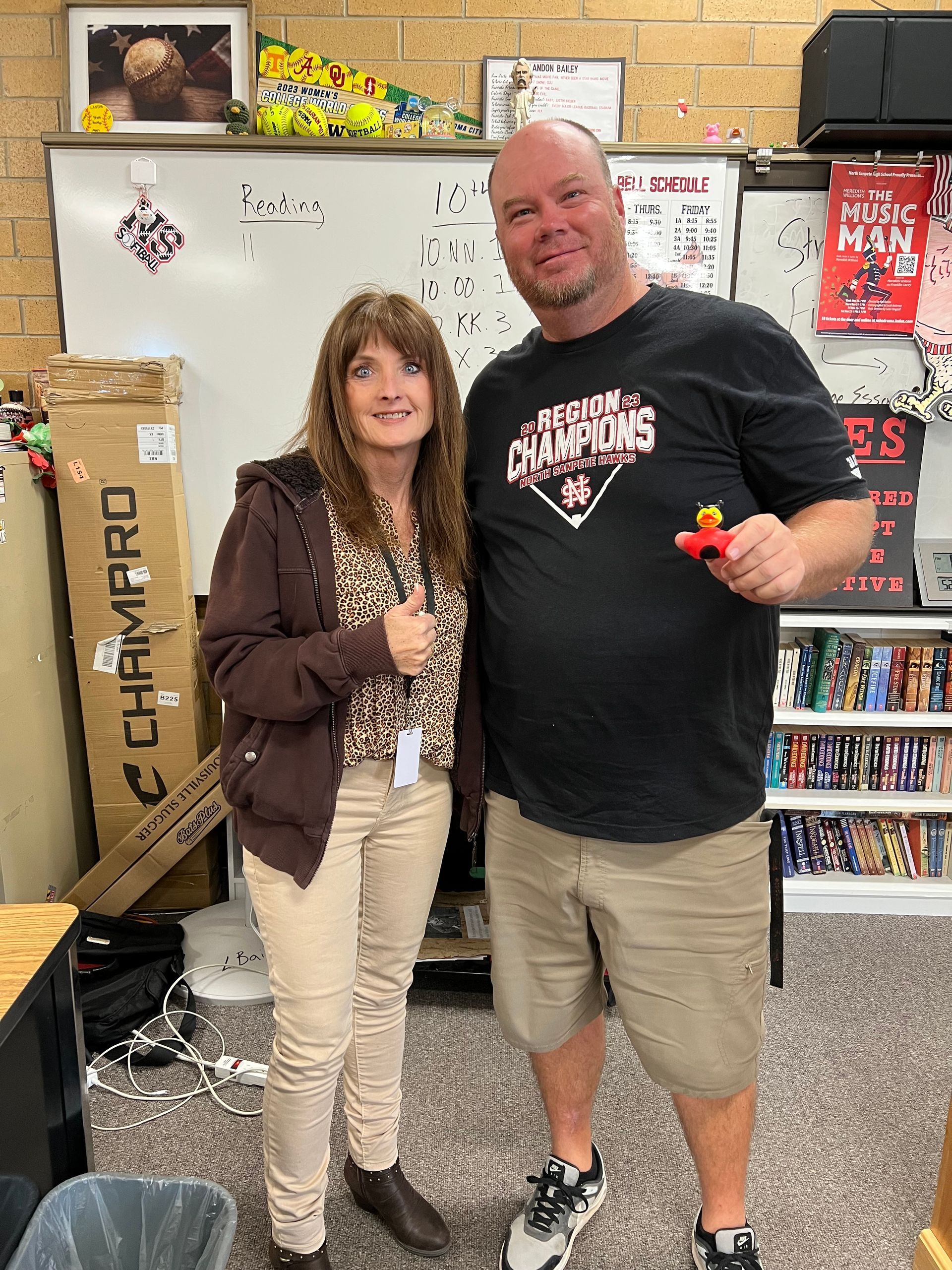 A man and a woman are standing next to each other in a classroom.