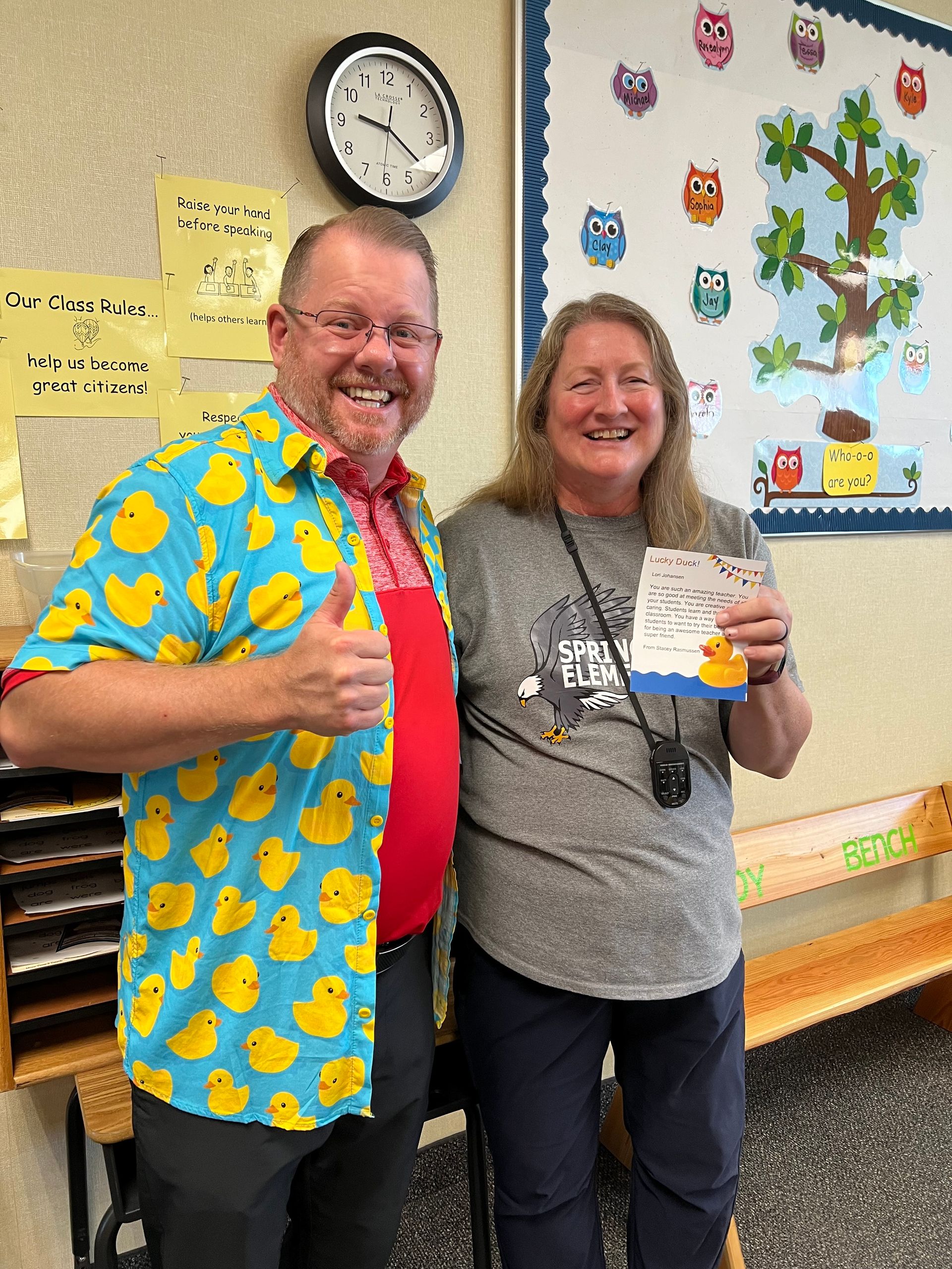 A man and a woman are standing next to each other in a classroom.