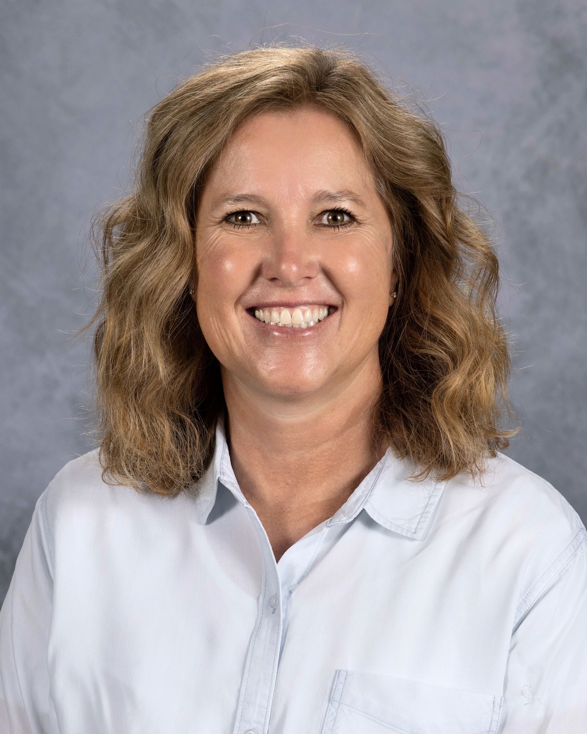 A woman in a blue shirt is smiling for the camera.