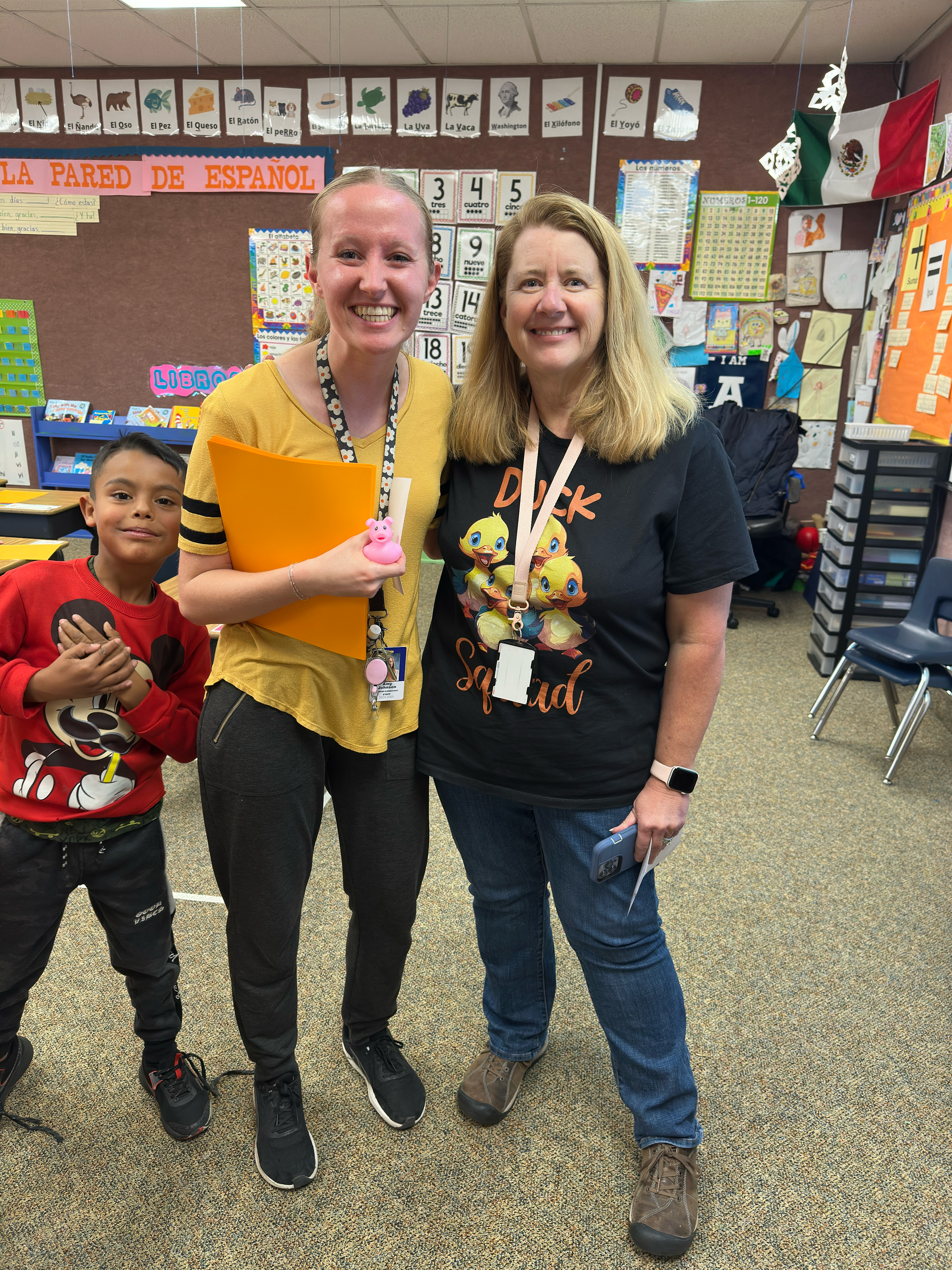 Two women and a child are posing for a picture in a classroom.