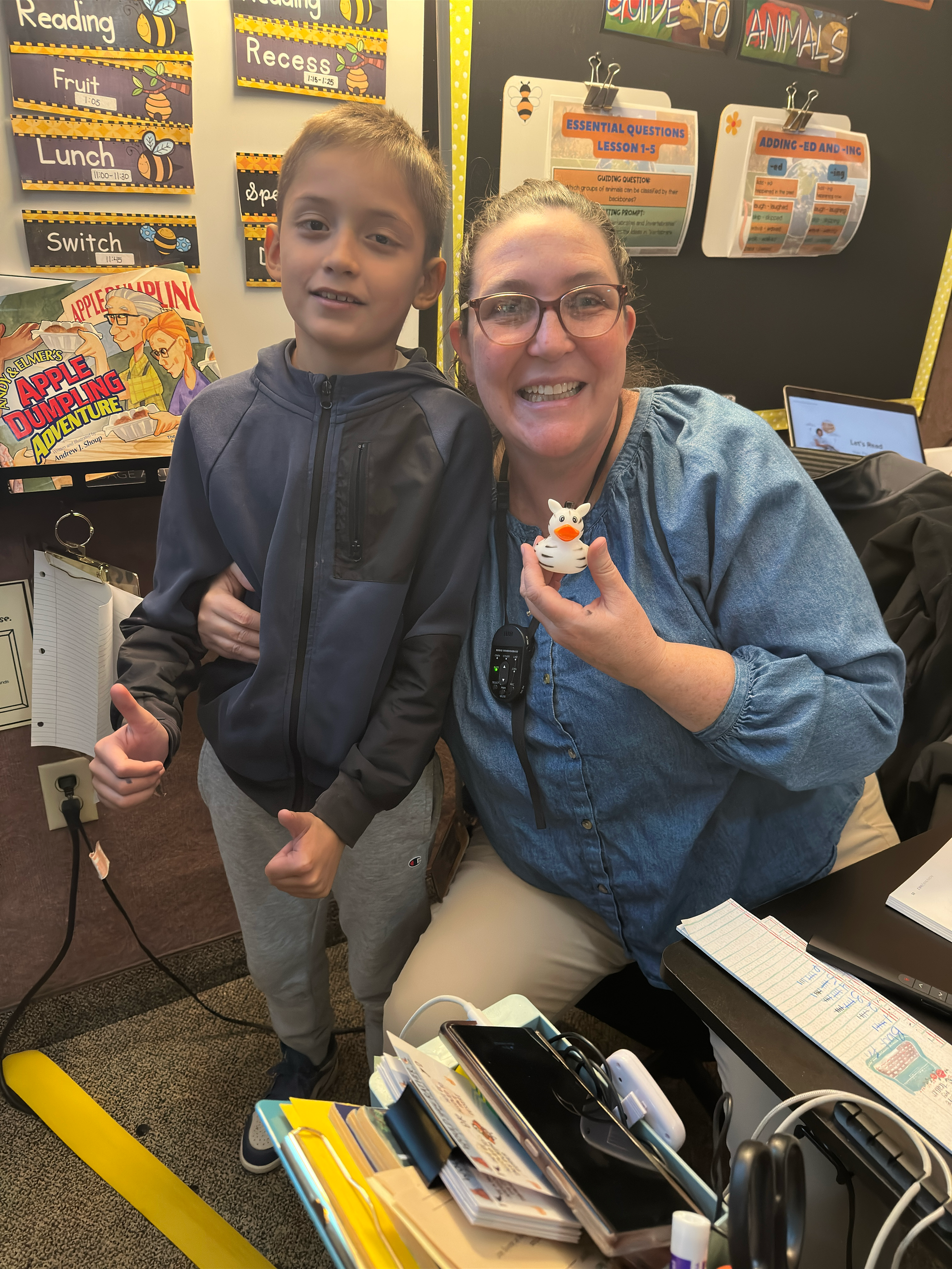 A woman and a boy are posing for a picture in a classroom.